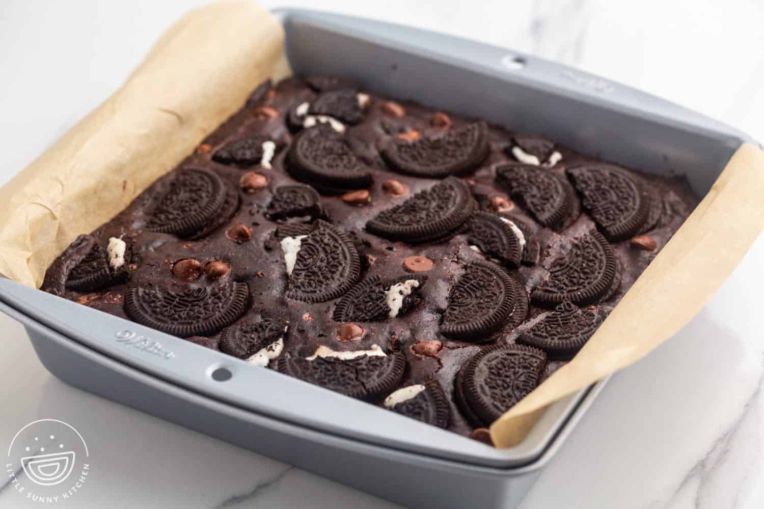 Baked oreo brownies in a square pan lined with parchment paper