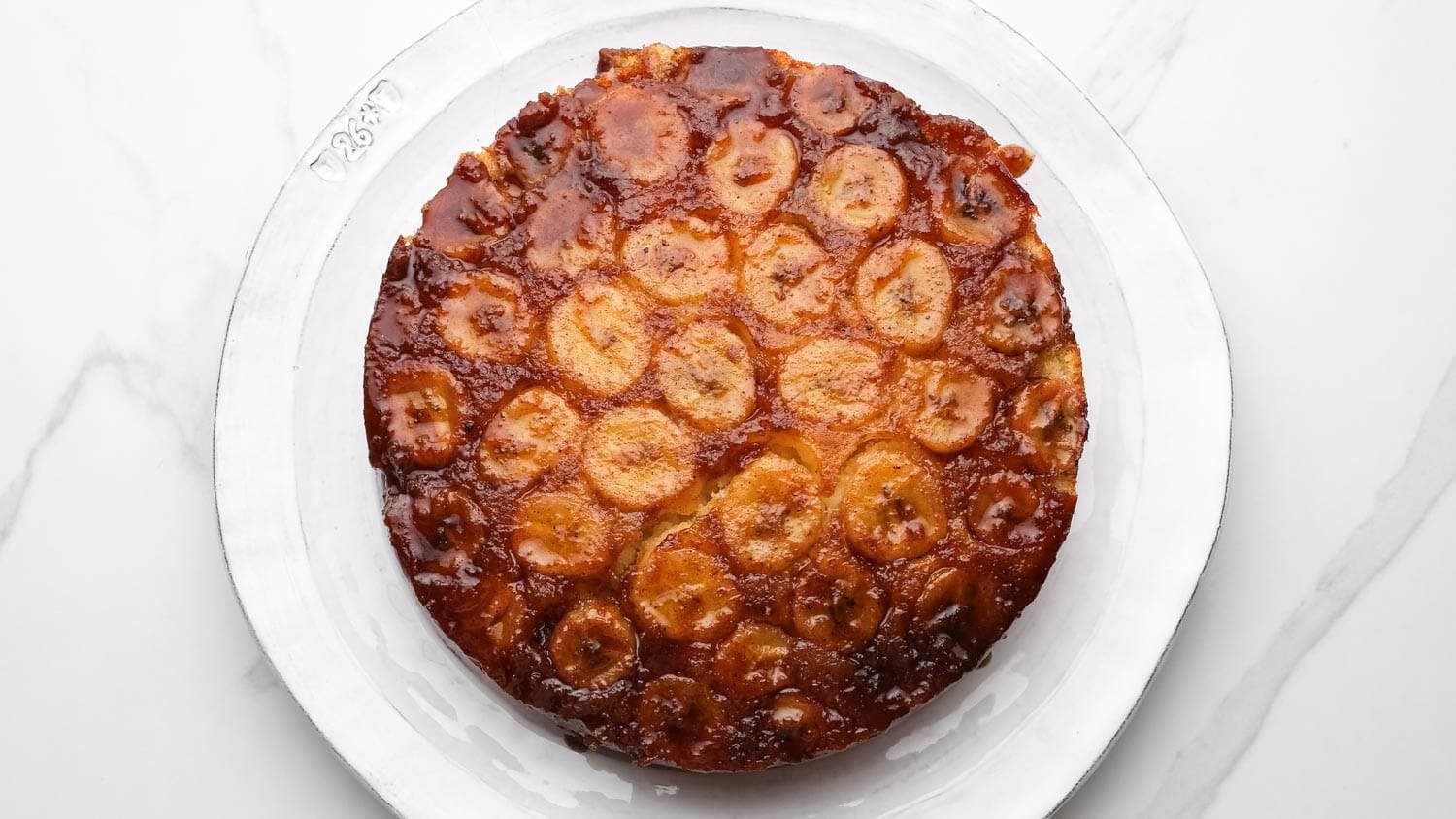 Banana upside down cake inverted onto a plate with caramelized banana topping on display.