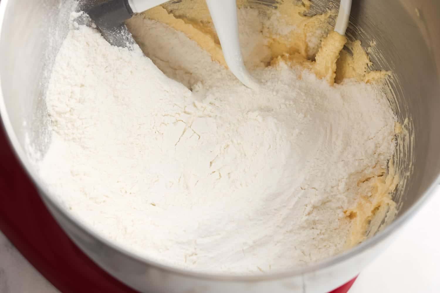 Flour added on top of creamed batter in mixing bowl, ready to be mixed.