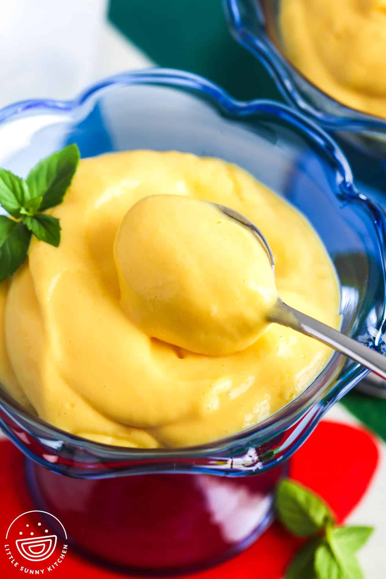 Creamy mango mousse served in a blue dessert cup with a spoon and mint garnish