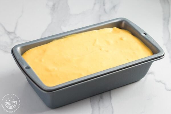 Mango mousse poured into a loaf pan, ready to be chilled