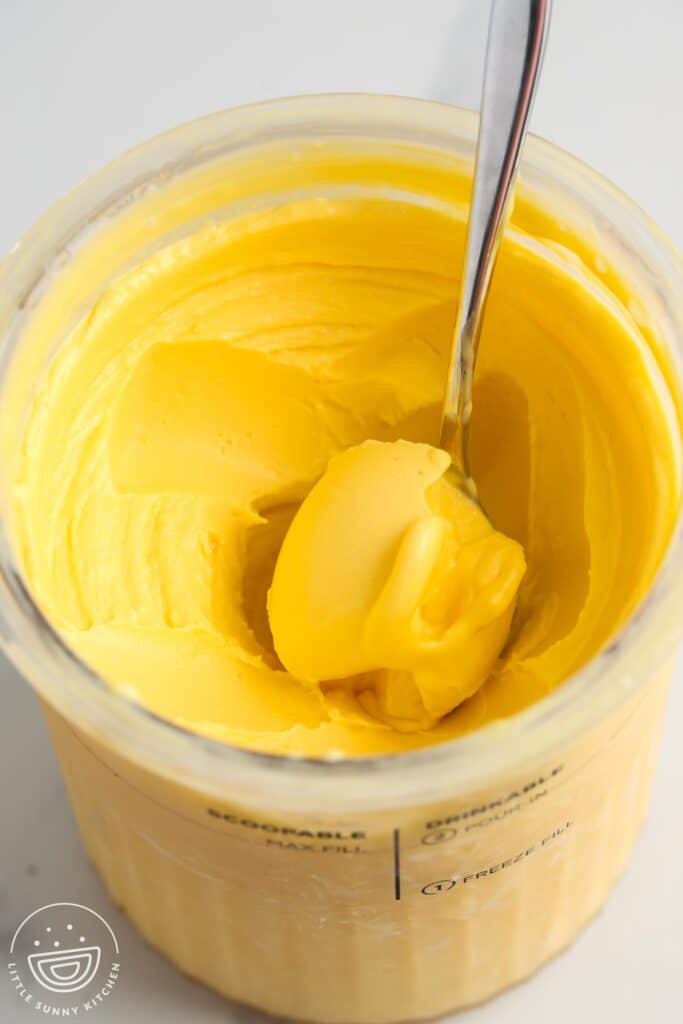 Mango frozen yogurt in a ninja creami tub with a spoon