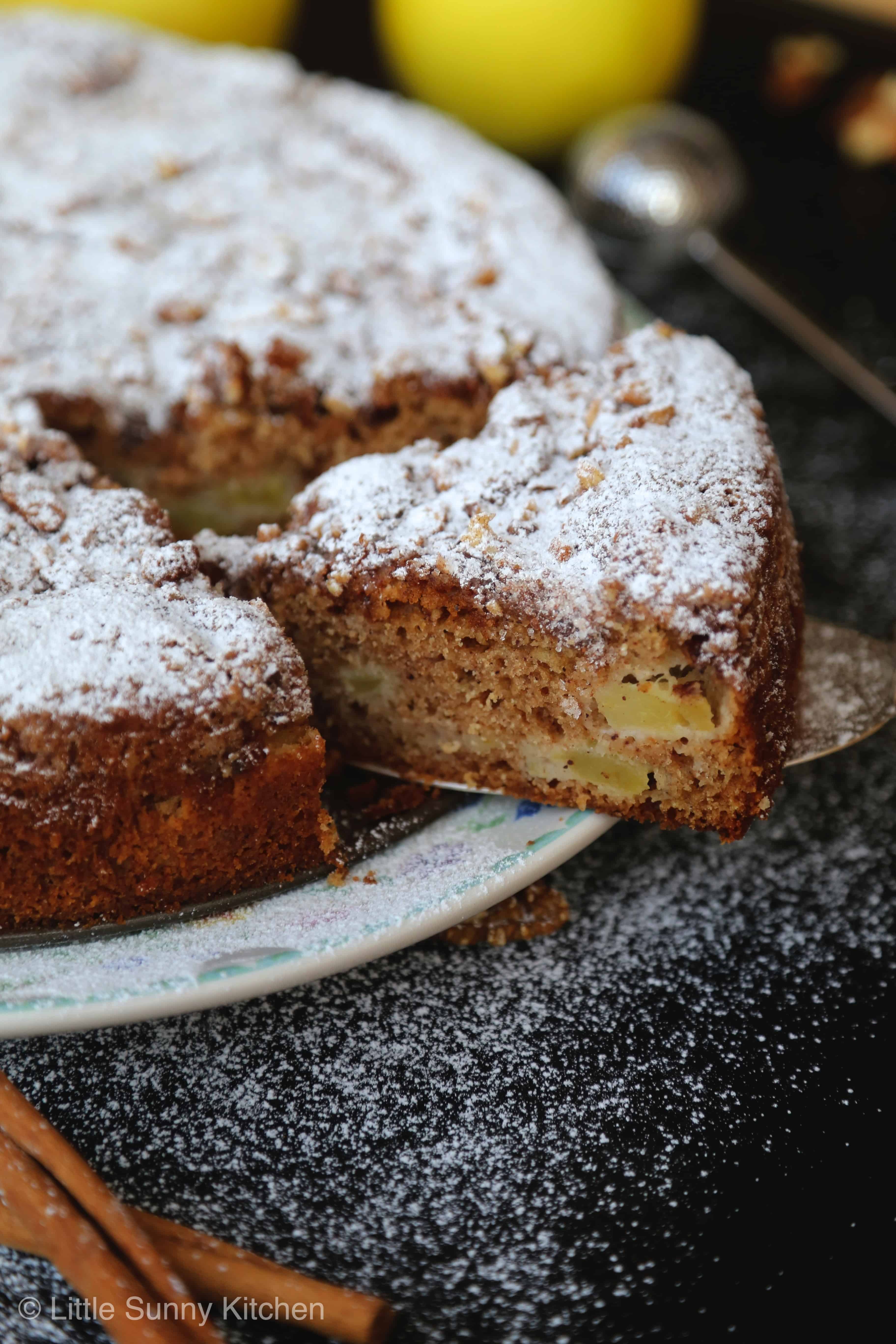 Cutting a slice of apple Sharlotka cake topped with powdered sugar.