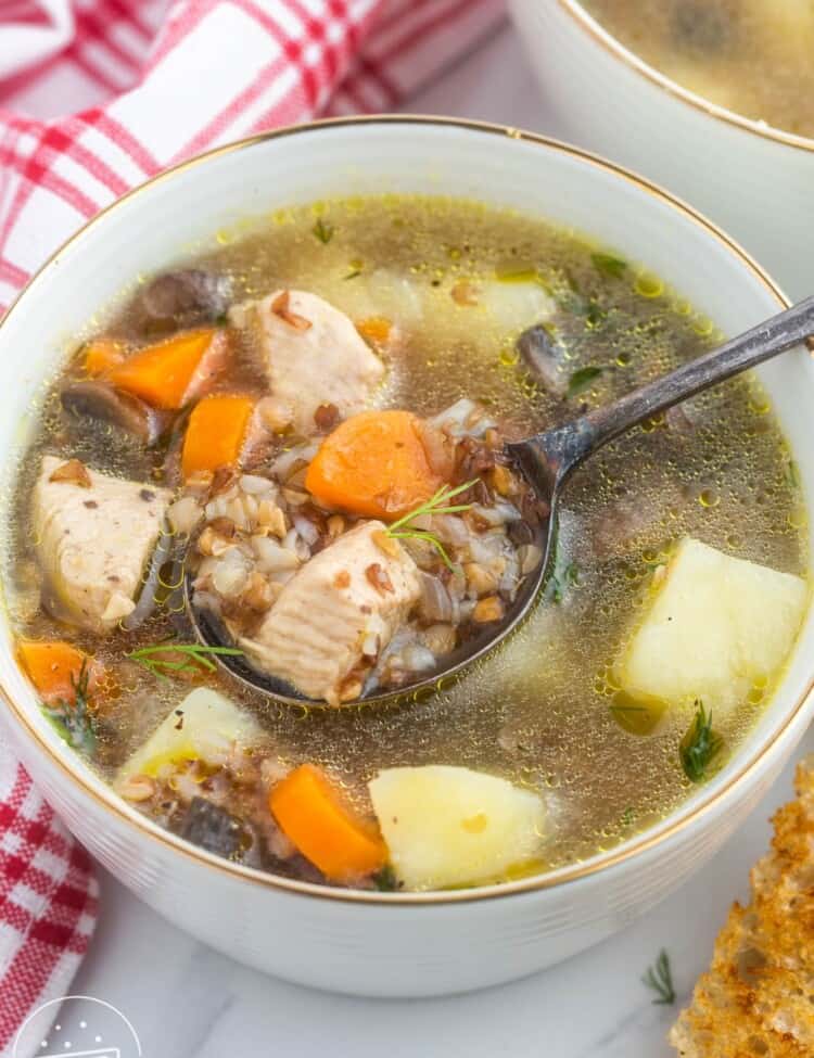 Angle shot of buckwheat soup with chicken in a white bowl with a spoon