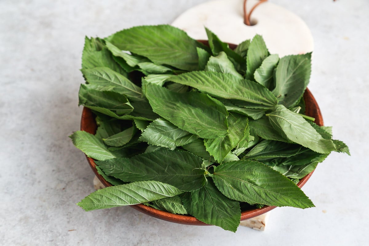 A bunch of molokhia leaves in a wooden bowl