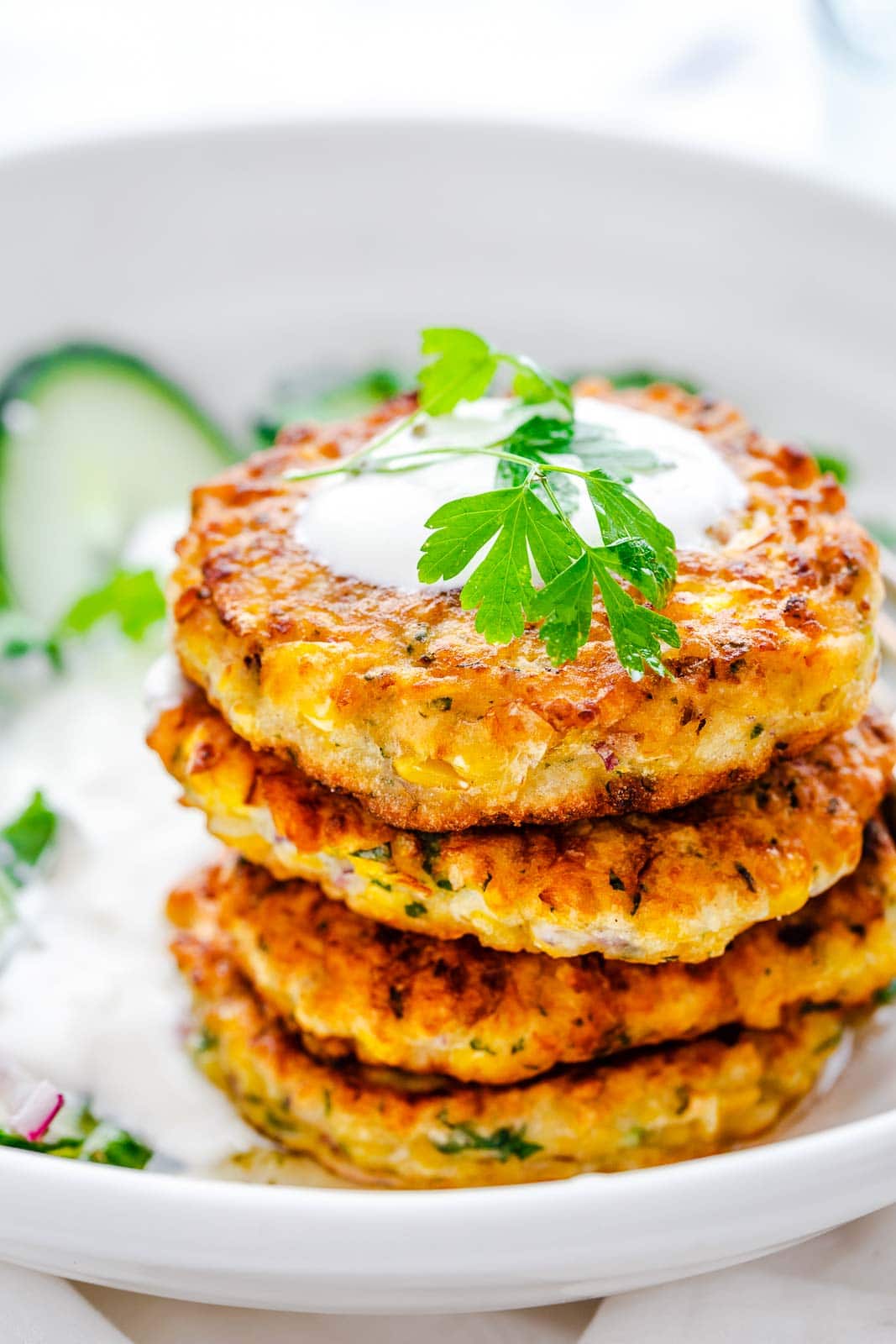 4 corn fritters stacked on each other in a white plate