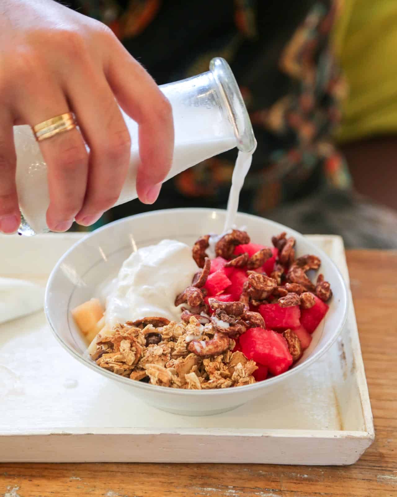 Pouring cinnamon cashew milk to a smoothie bowl