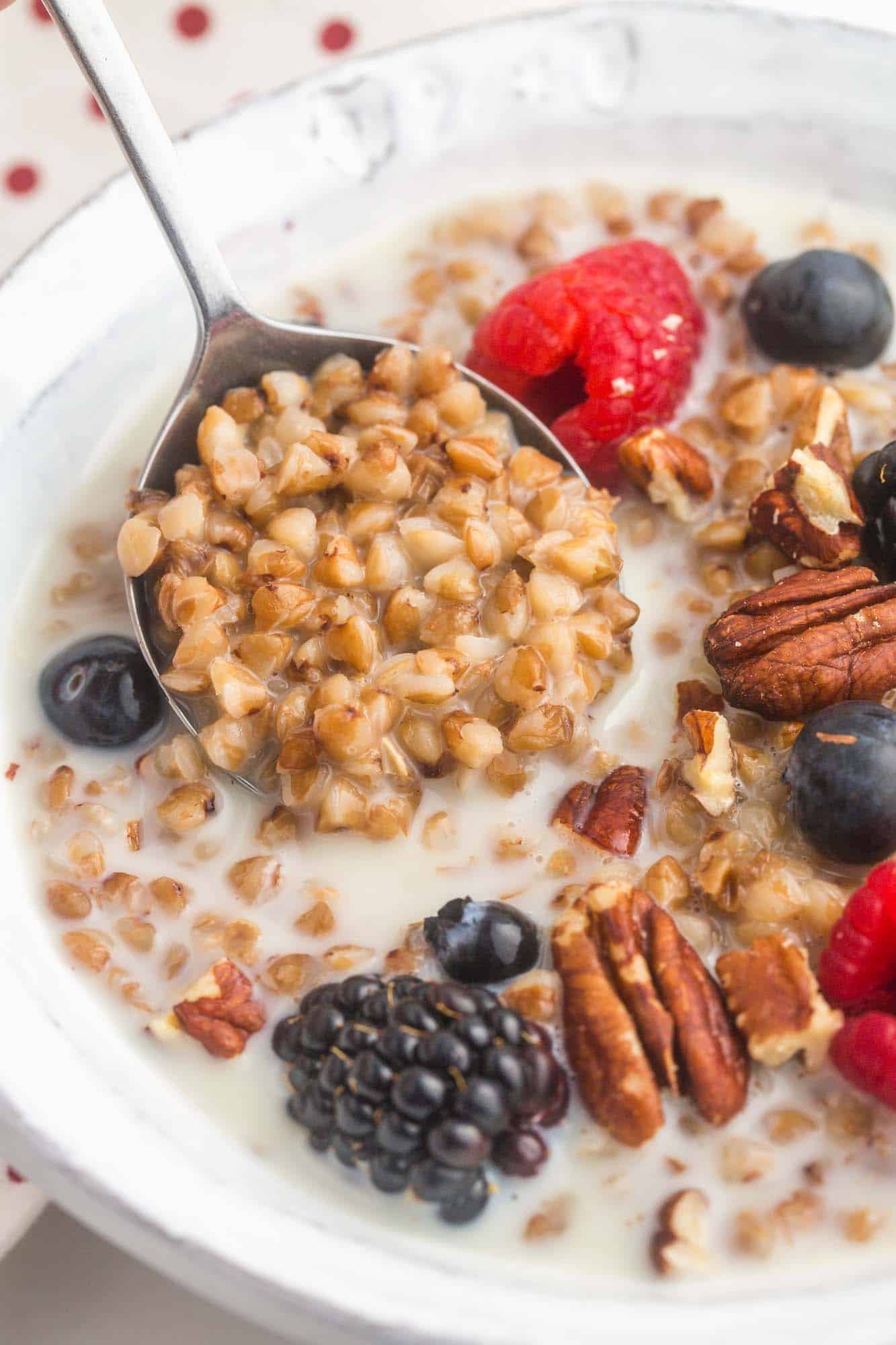 Close up shot of buckwheat porridge with fresh fruit, and a spoonful.