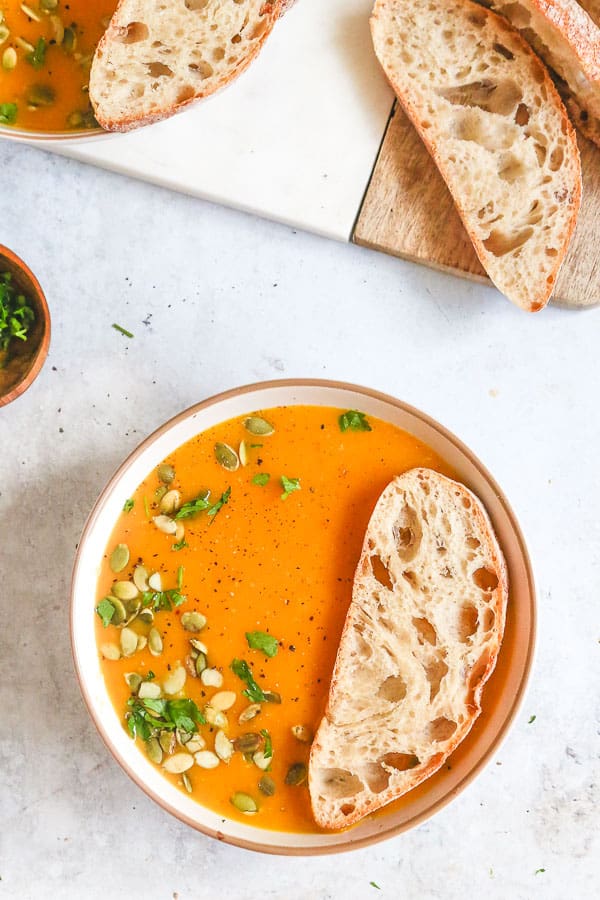 Butternut squash soup served in a white bowl with toasted bread slice 