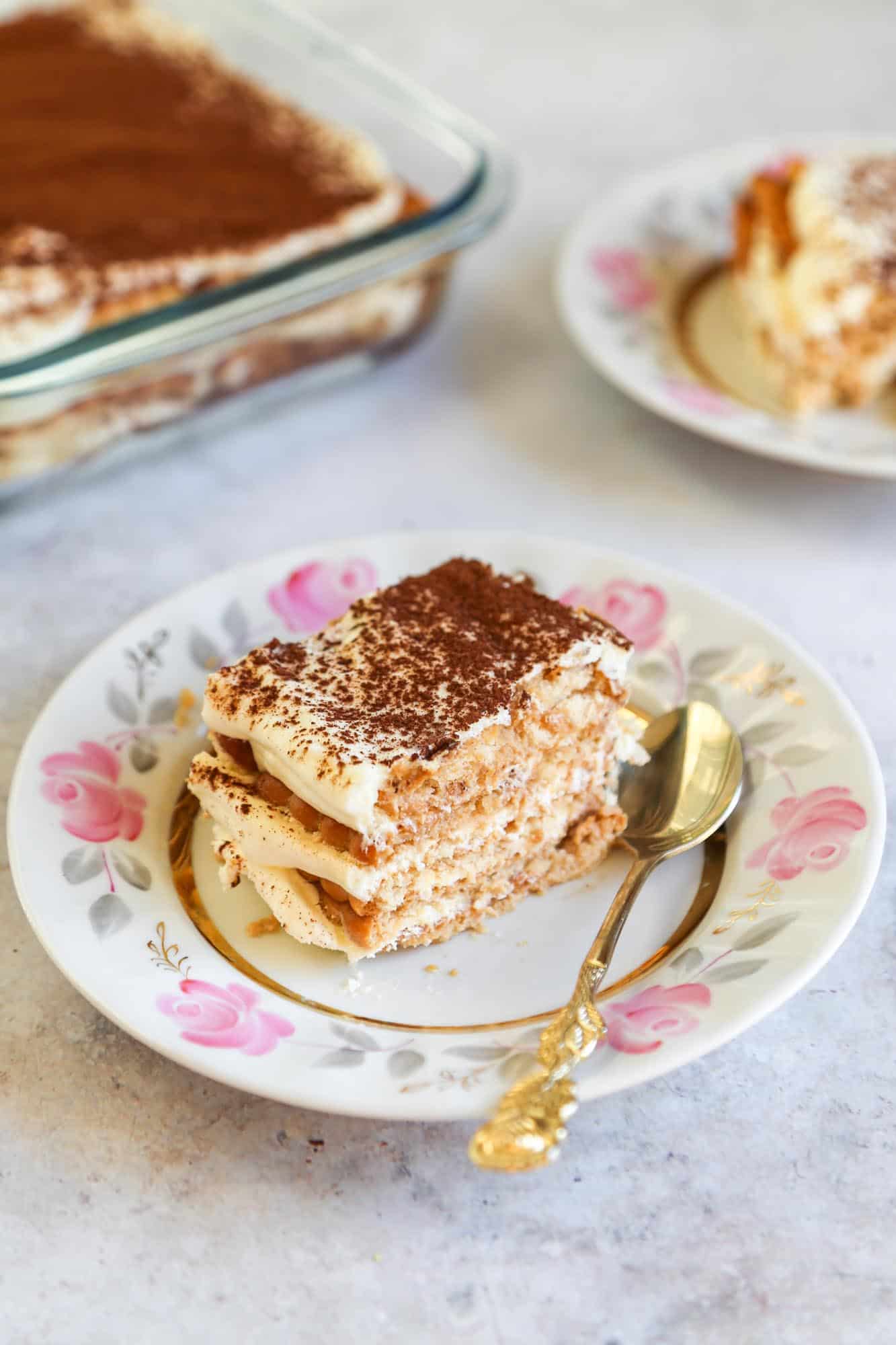 A slice of Nescafe cake served on a cake plate with a golden spoon