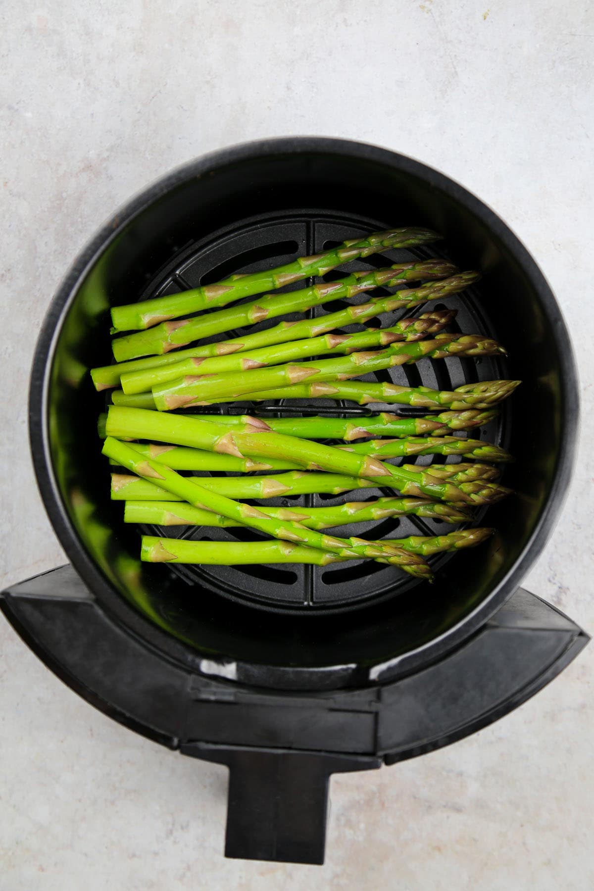 Fresh asparagus tips placed in the air fryer basket