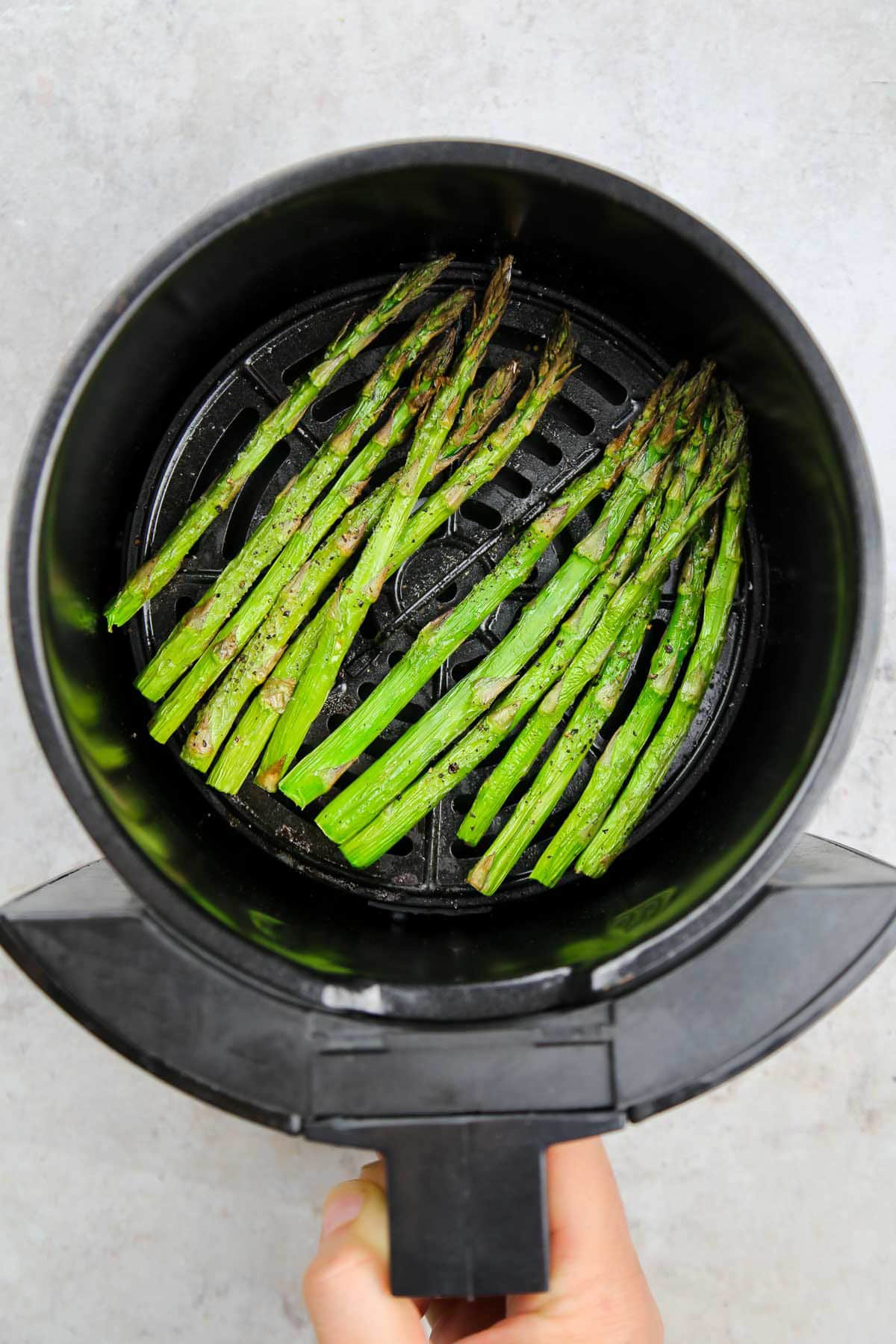 Ready and crispy asparagus in the air fryer basket.