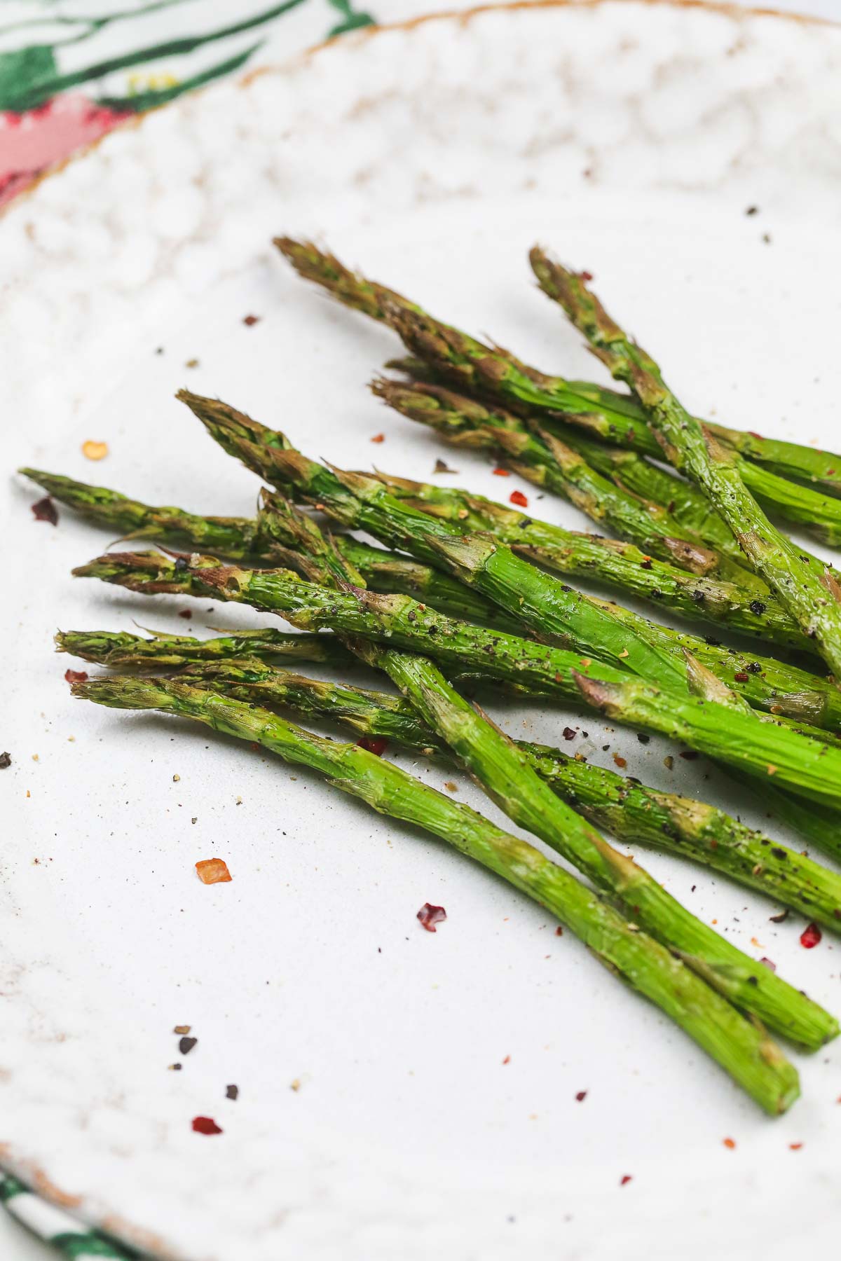 Air Fried asparagus tips topped with chilli flakes on a white plate