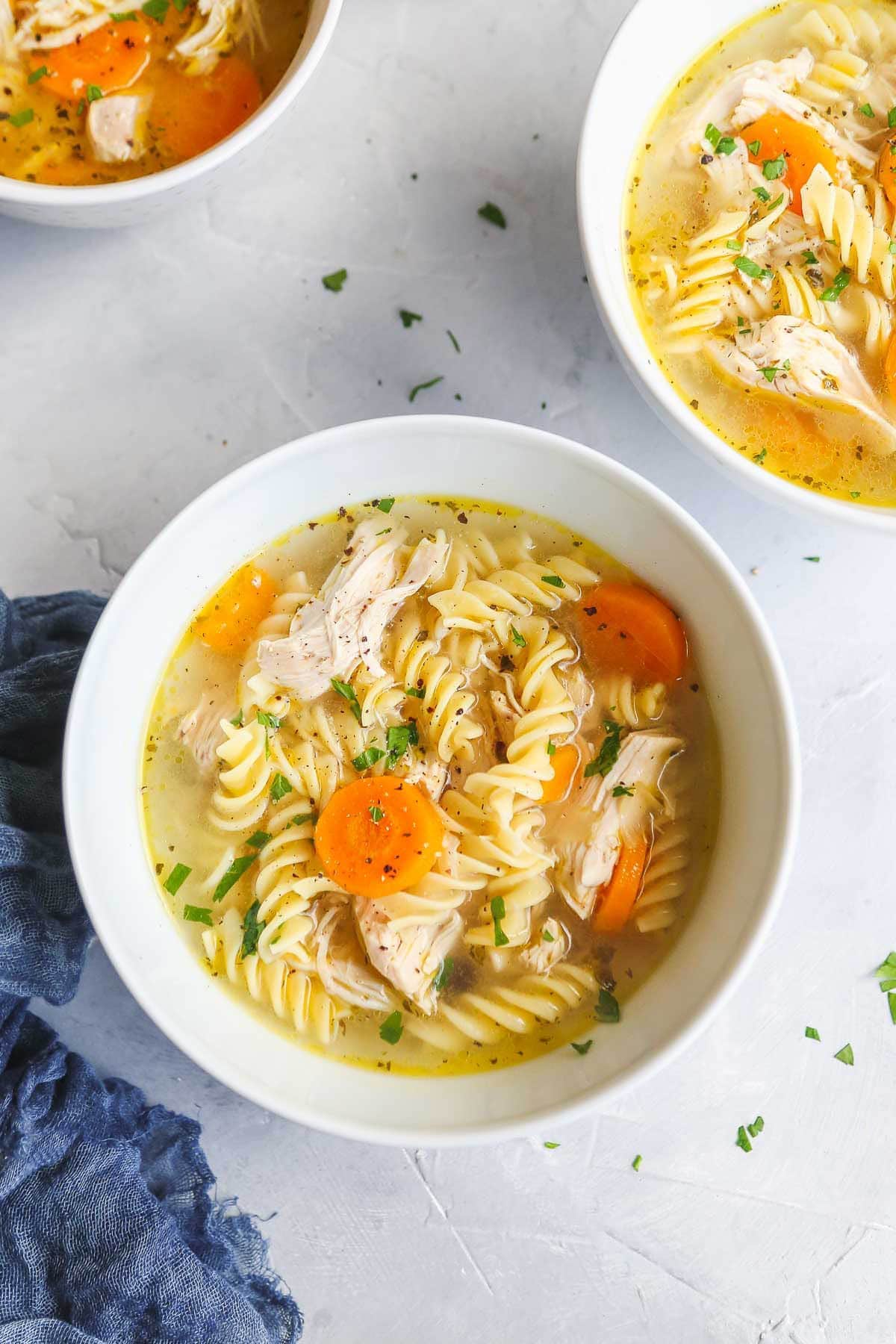 A bowl of Instant Pot Chicken Soup and a navy towel