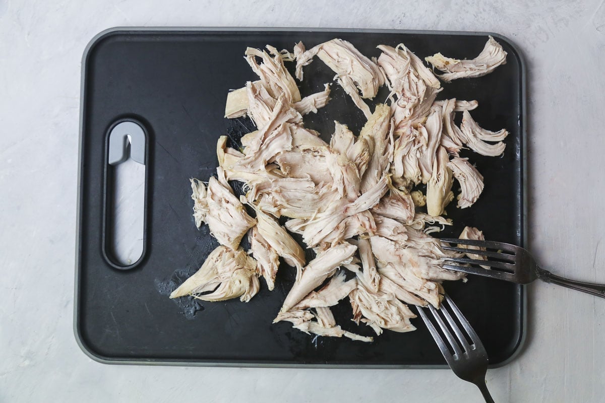 shredded chicken on a black cutting board