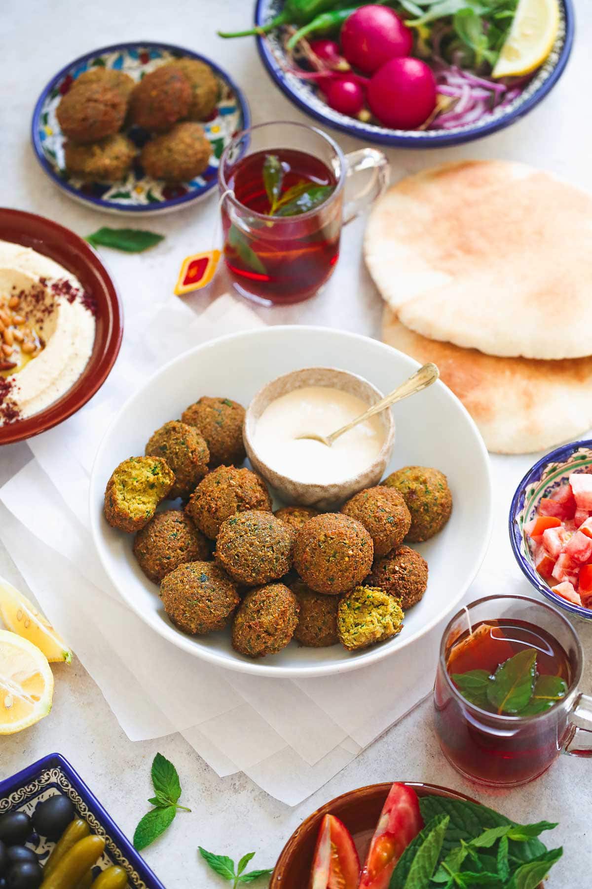 Jordanian breakfast spread with a bowl of falafel and tahini sauce, mint tea, pita bread and hummus.