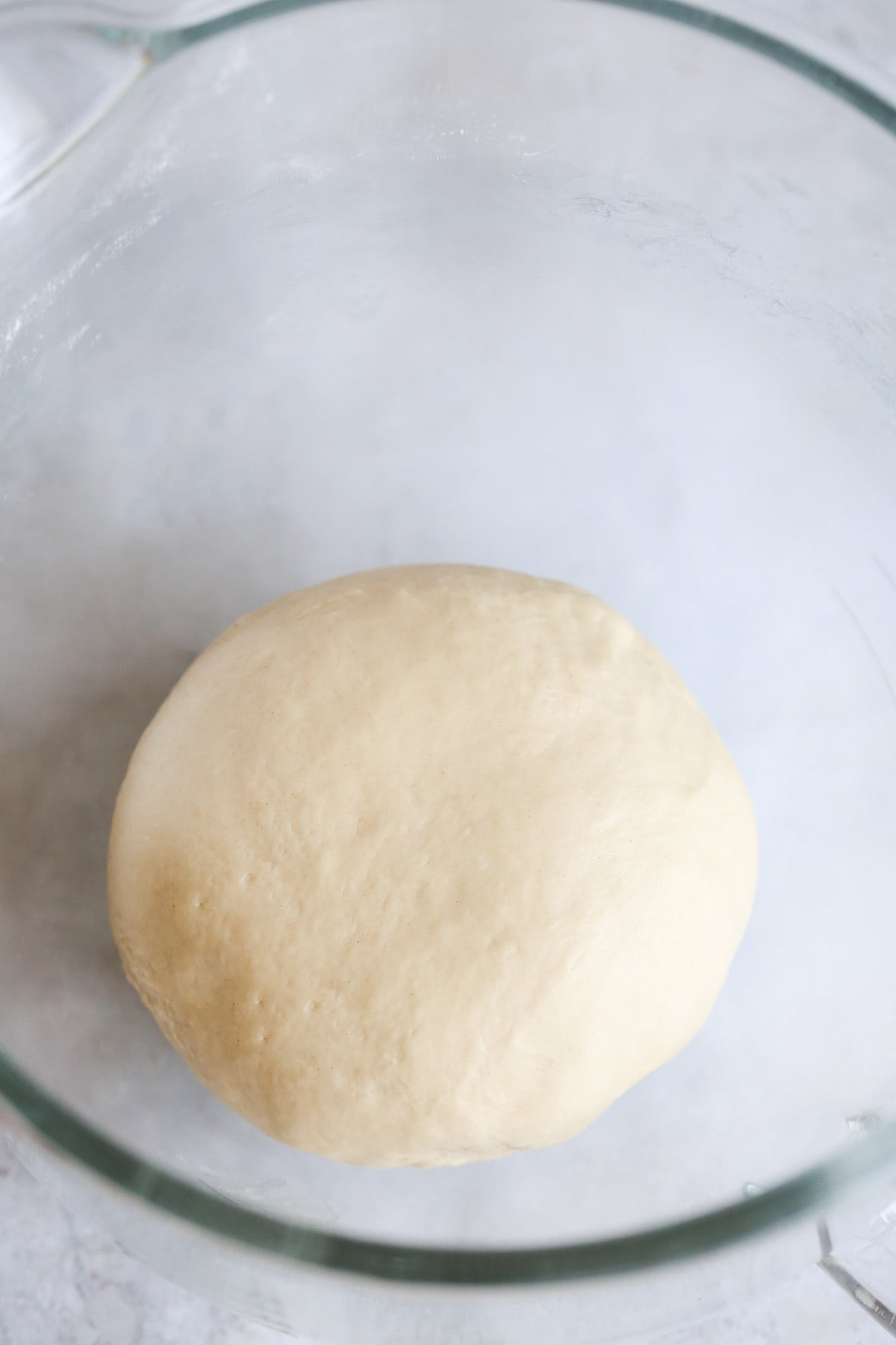 A dough ball in a glass bowl