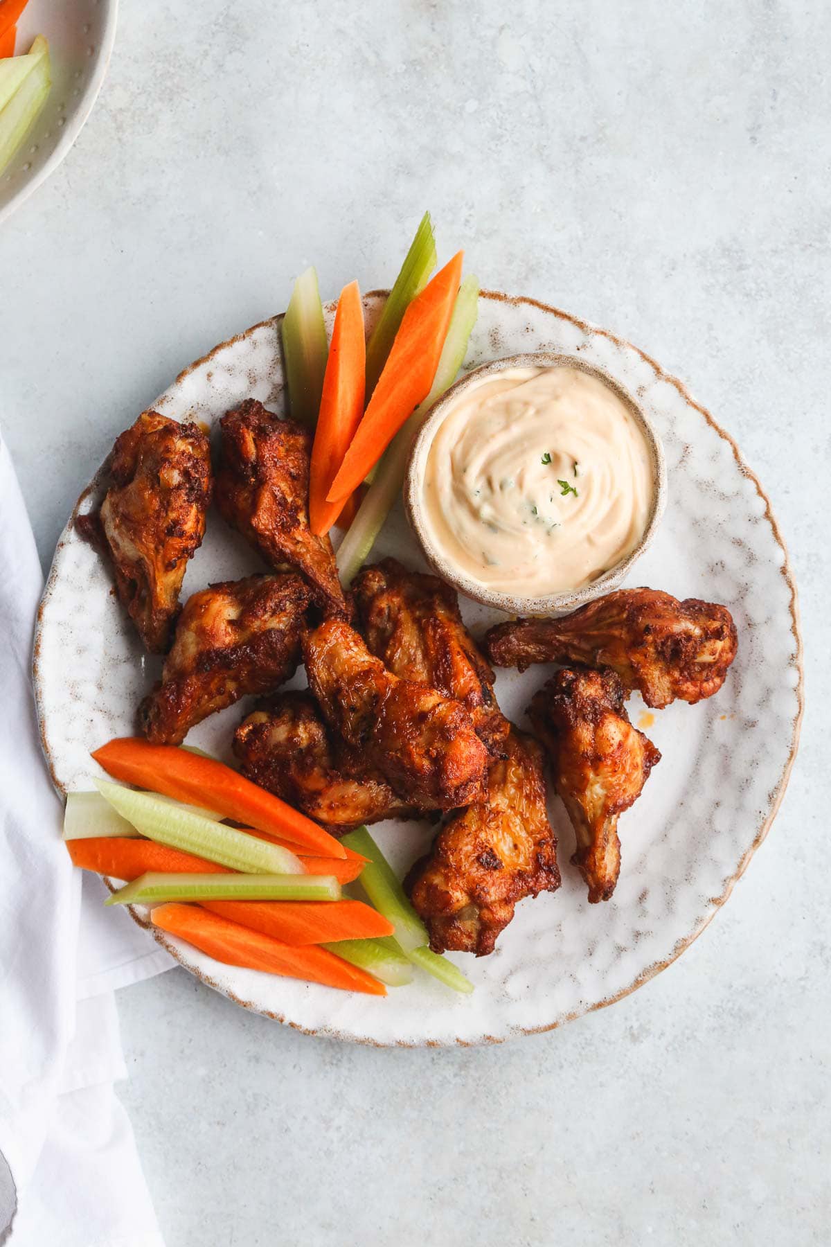 A plate with chicken wings, carrot and celery sticks and ranch dip