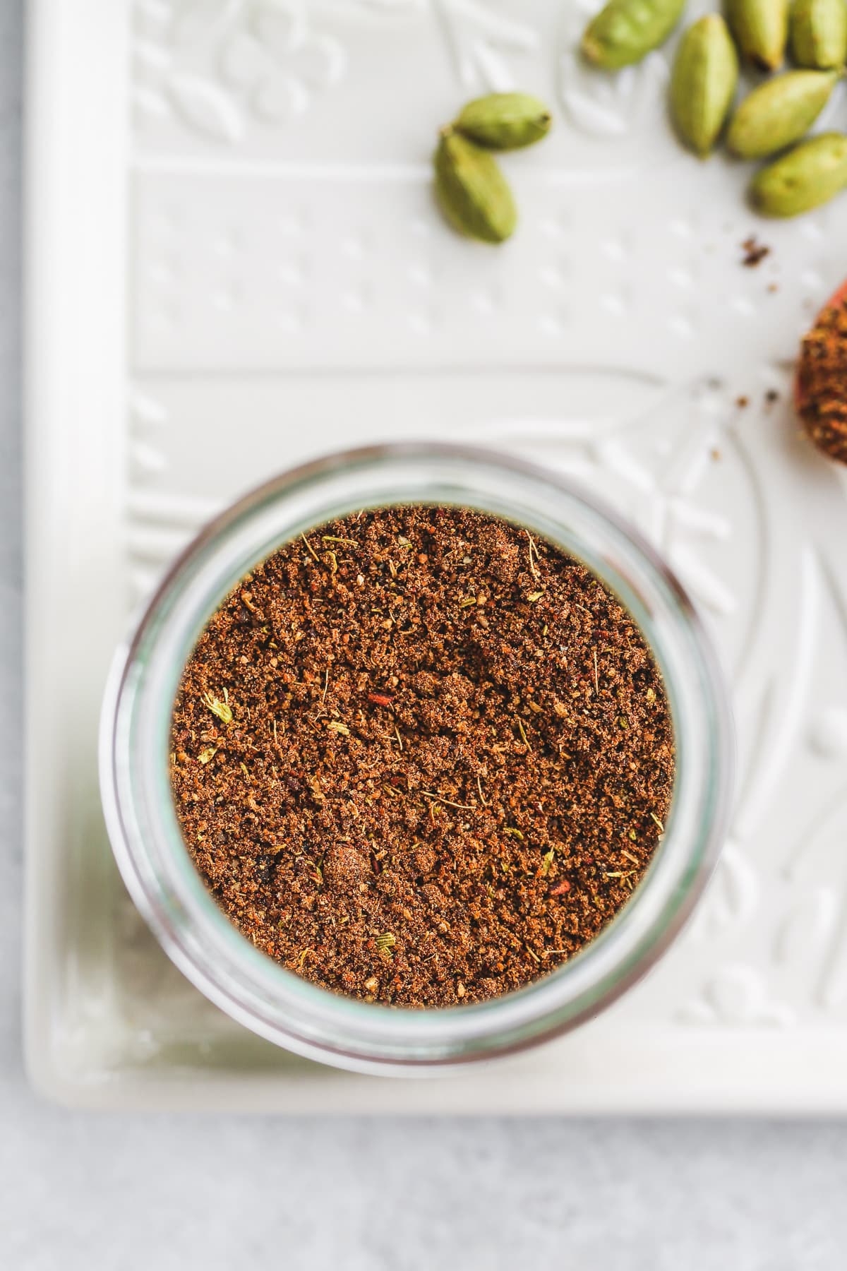 A close up of a baharat spice blend jar on a white glass try