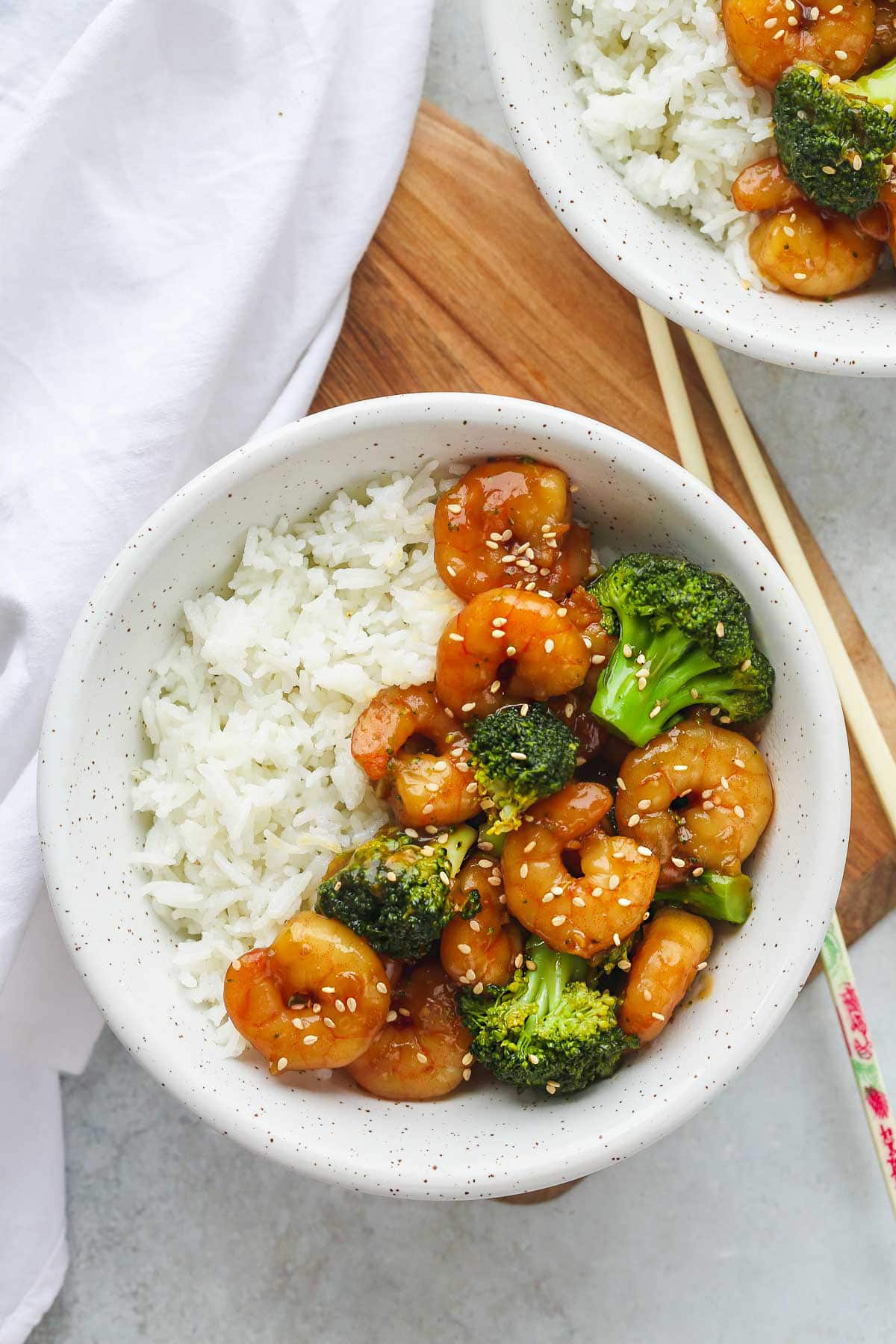 Shrimp and Broccoli stir fry in a white bowl with chop sticks