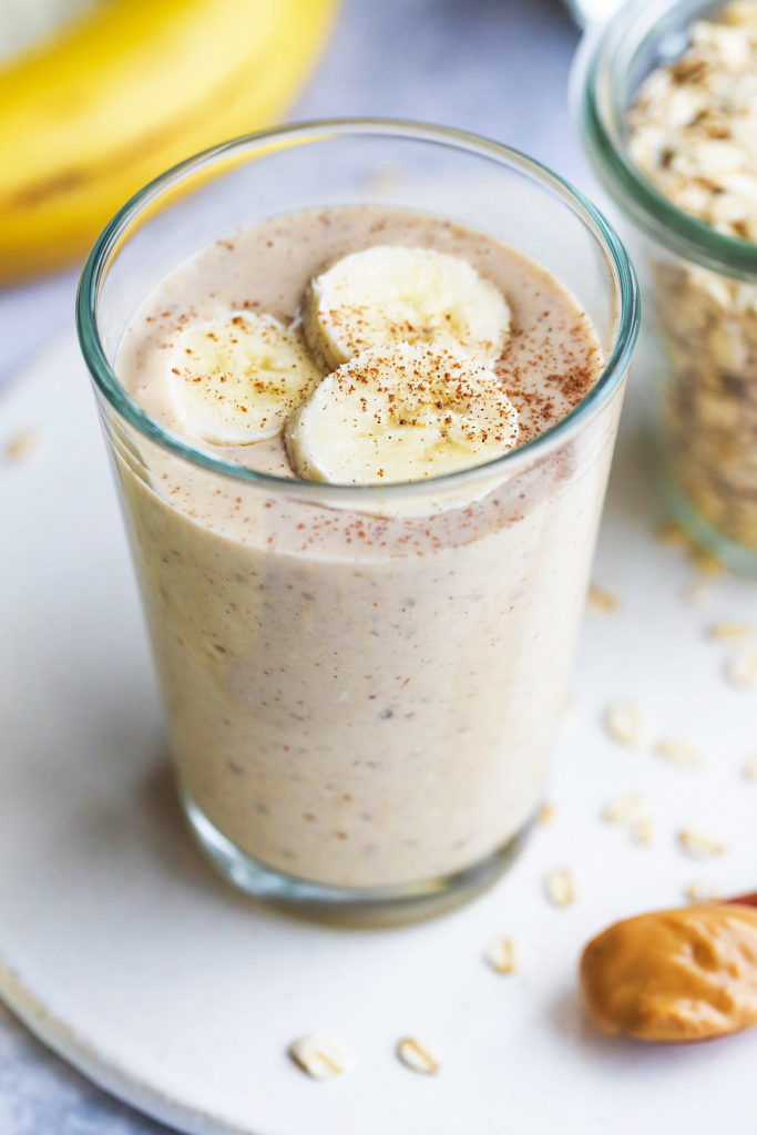 Banana oatmeal smoothie glass topped with banana slices and a sprinkle cinnamon  