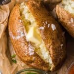 Close-up of an air fryer baked potato with crispy skin, fluffy interior, and butter melting into the center