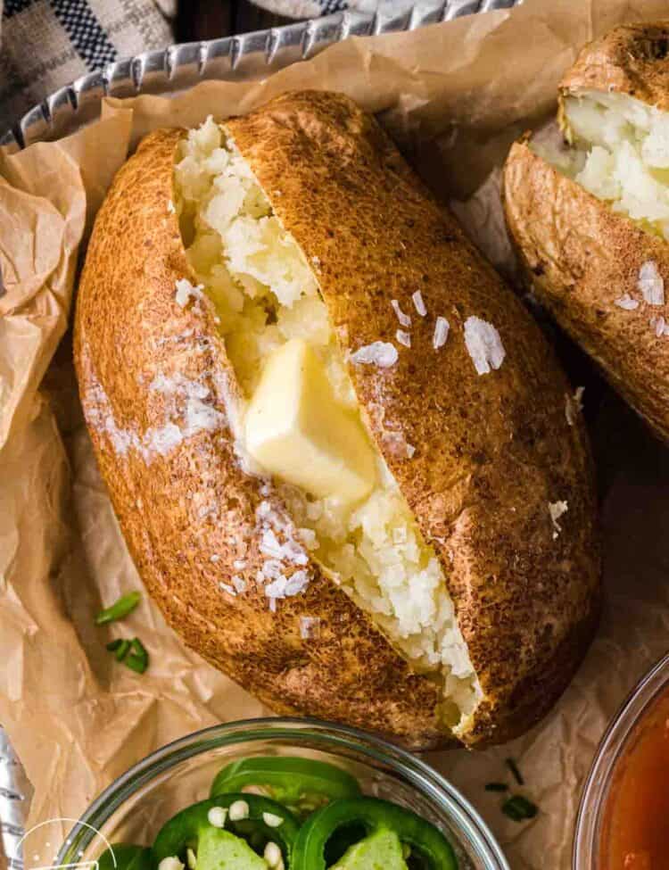 Close-up of an air fryer baked potato with crispy skin, fluffy interior, and butter melting into the center