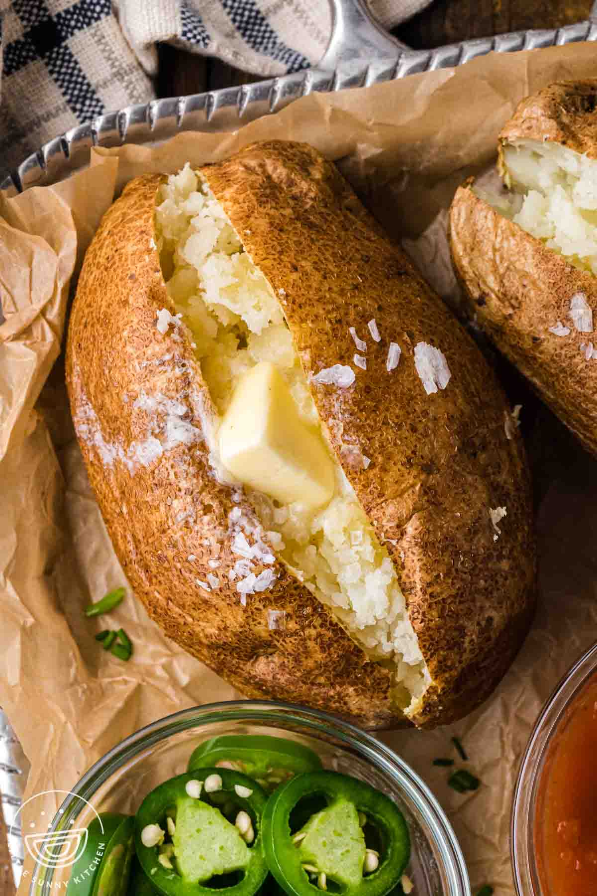 Close-up of an air fryer baked potato with crispy skin, fluffy interior, and butter melting into the center
