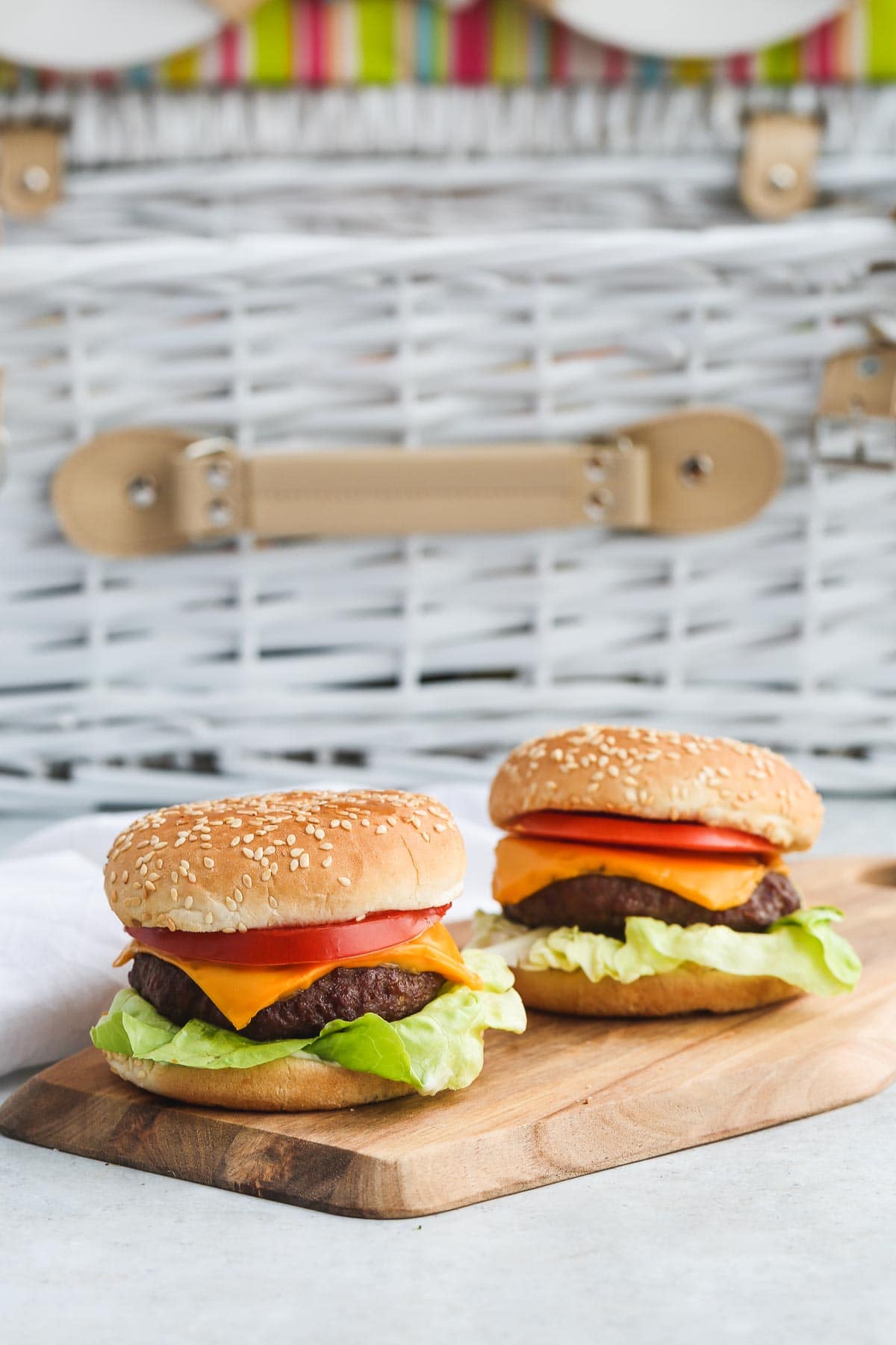 Two hamburgers on a wooden board.