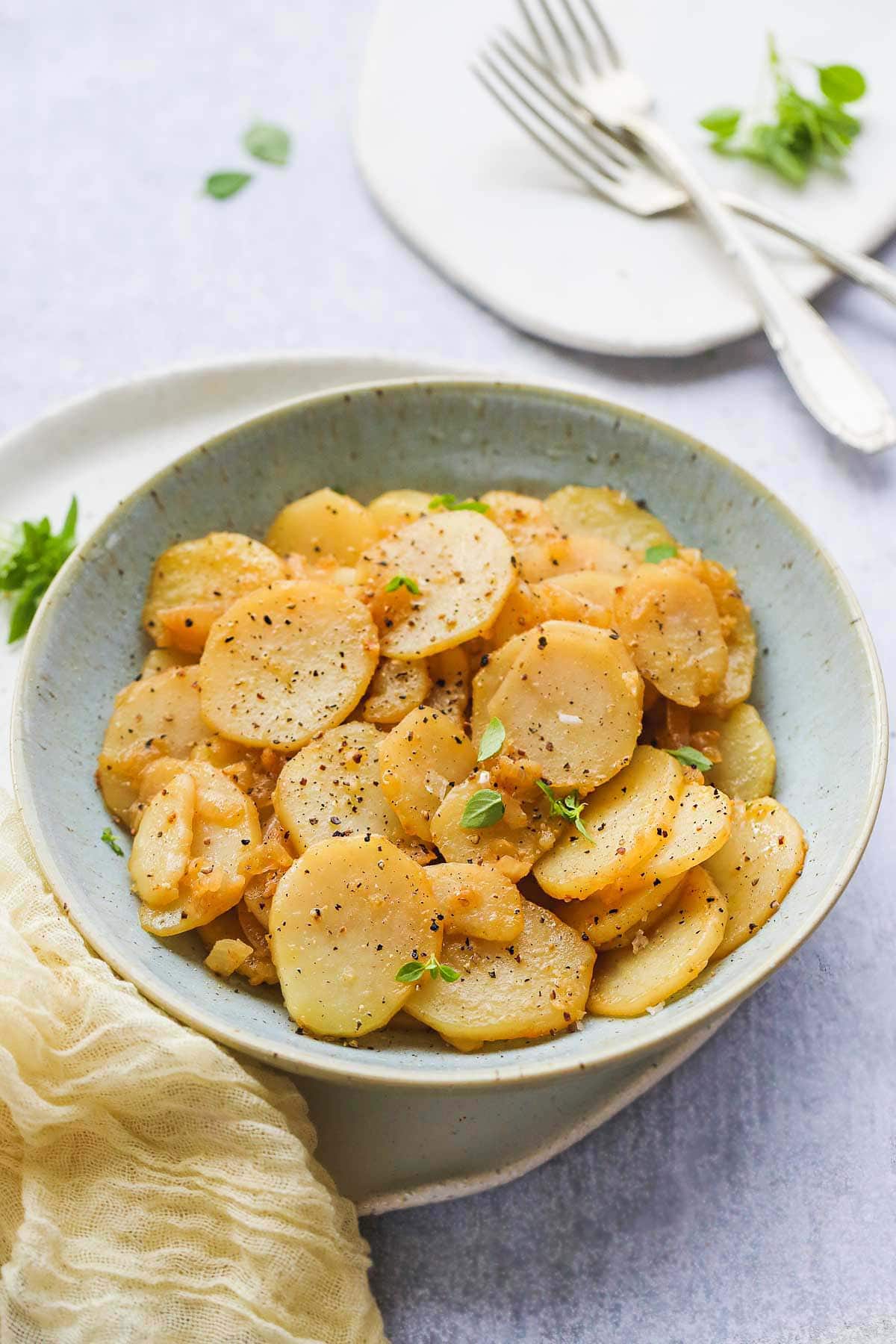 A bowl of Smothered Potatoes and a yellow kitchen towel