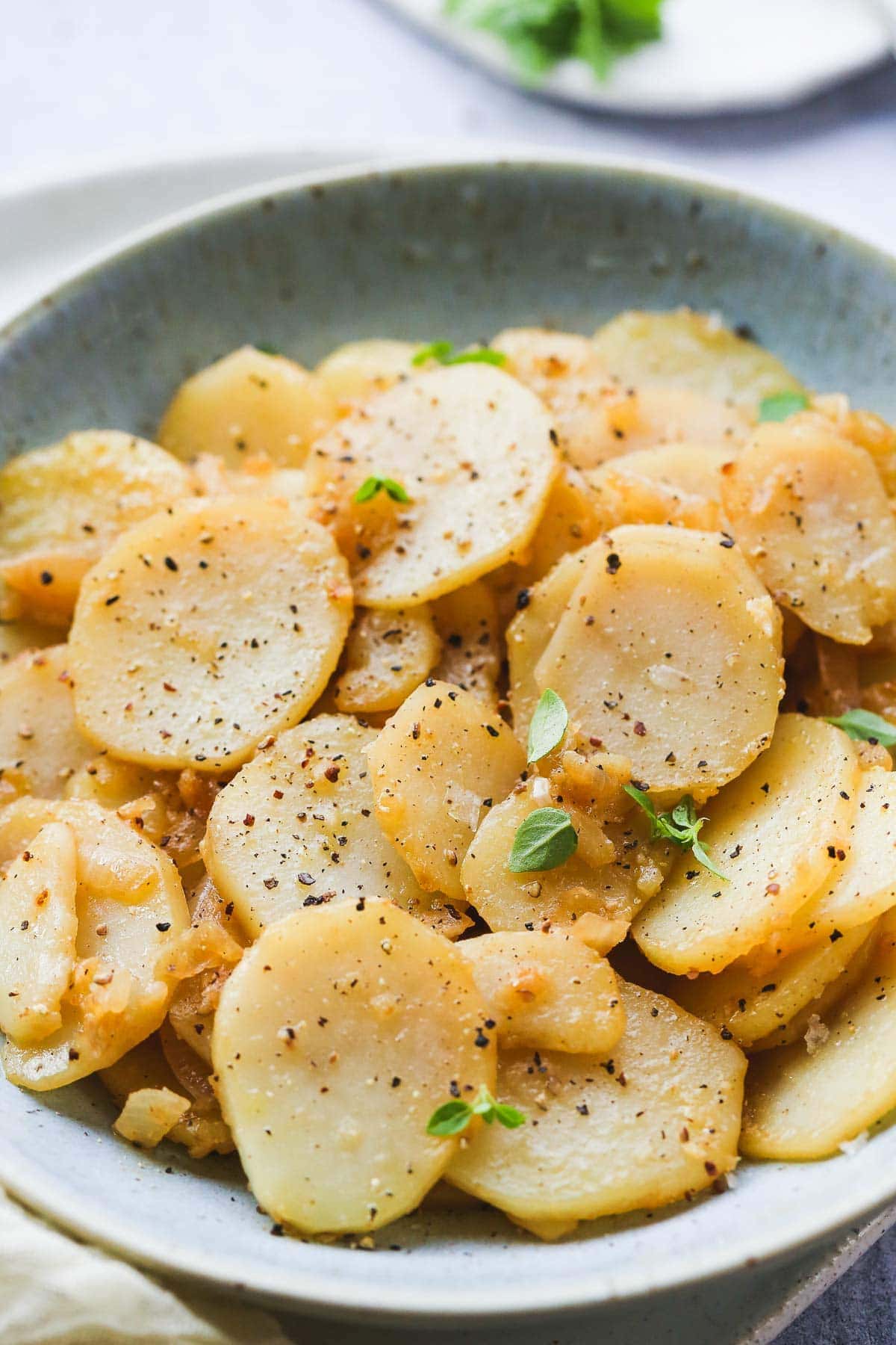 A close up shot of smothered Potatoes with small basil leaves