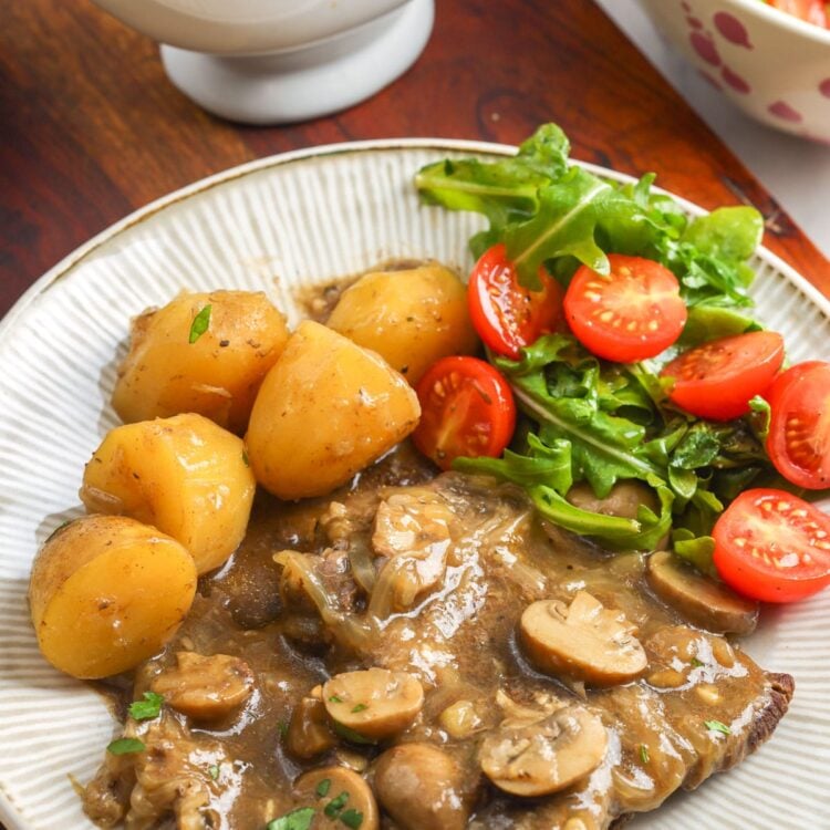 Instant Pot cube steak with mushroom and onion gravy, baby potatoes, and a fresh side salad.