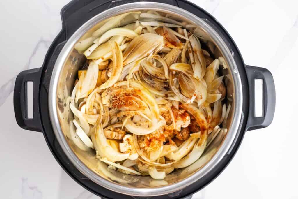 Baby potatoes, mushrooms, onions, garlic, and seasonings layered over cube steak in the Instant Pot.