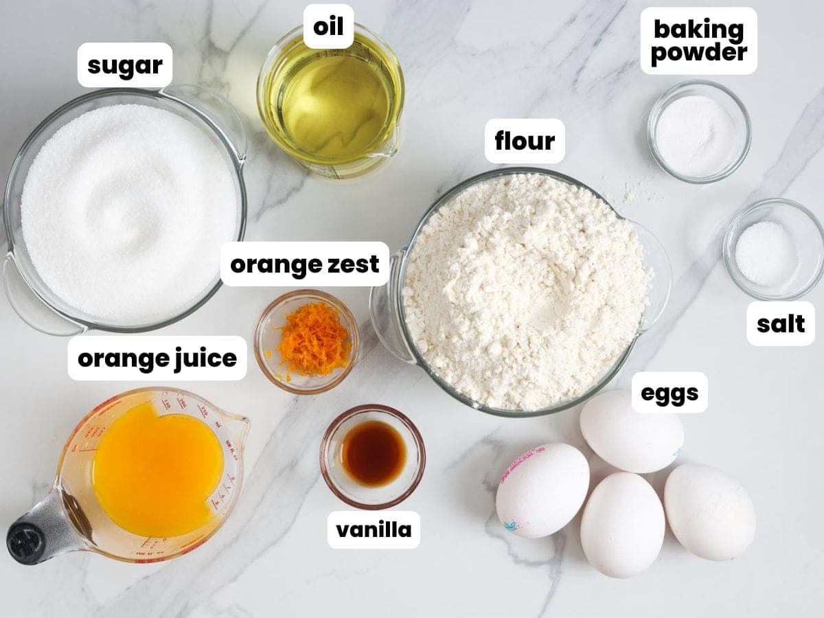 Ingredients needed to make orange juice cake in small bowls, including flour, orange juice and zest, oil, eggs and more.