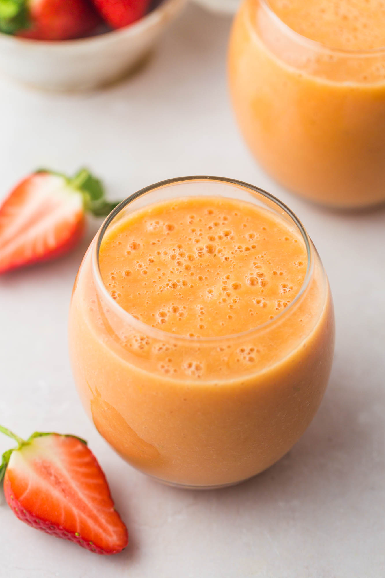 2 glasses of strawberry mango smoothie and sliced strawberries