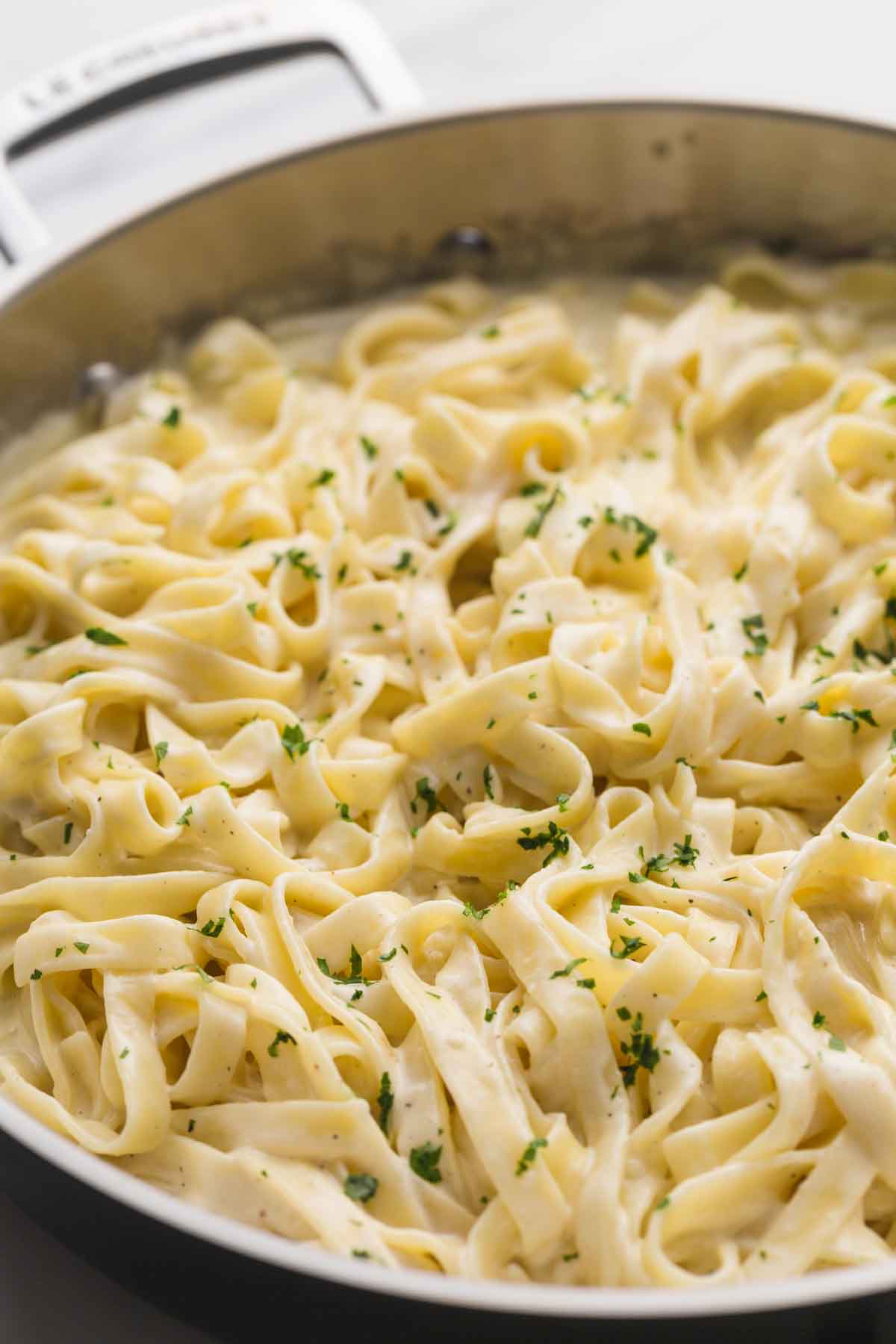 A stainless steel pan with fettuccine alfredo