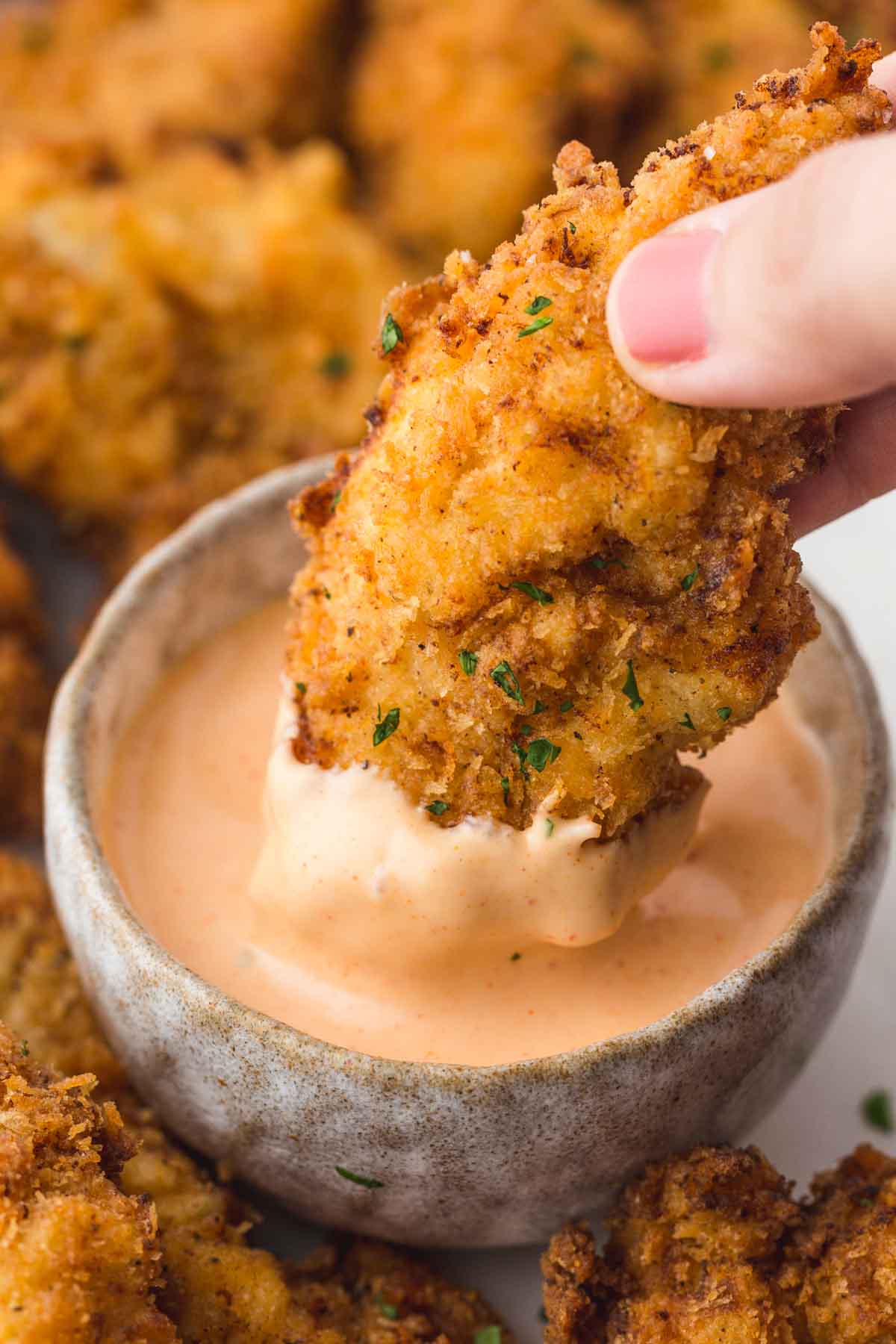 Dipping a crispy chicken tender in Cane's sauce