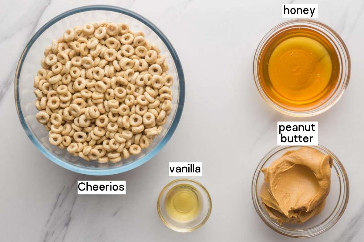 Overhead shot of ingredients needed to make cereal bars including cheerios, honey, creamy peanut butter, and vanilla extract.