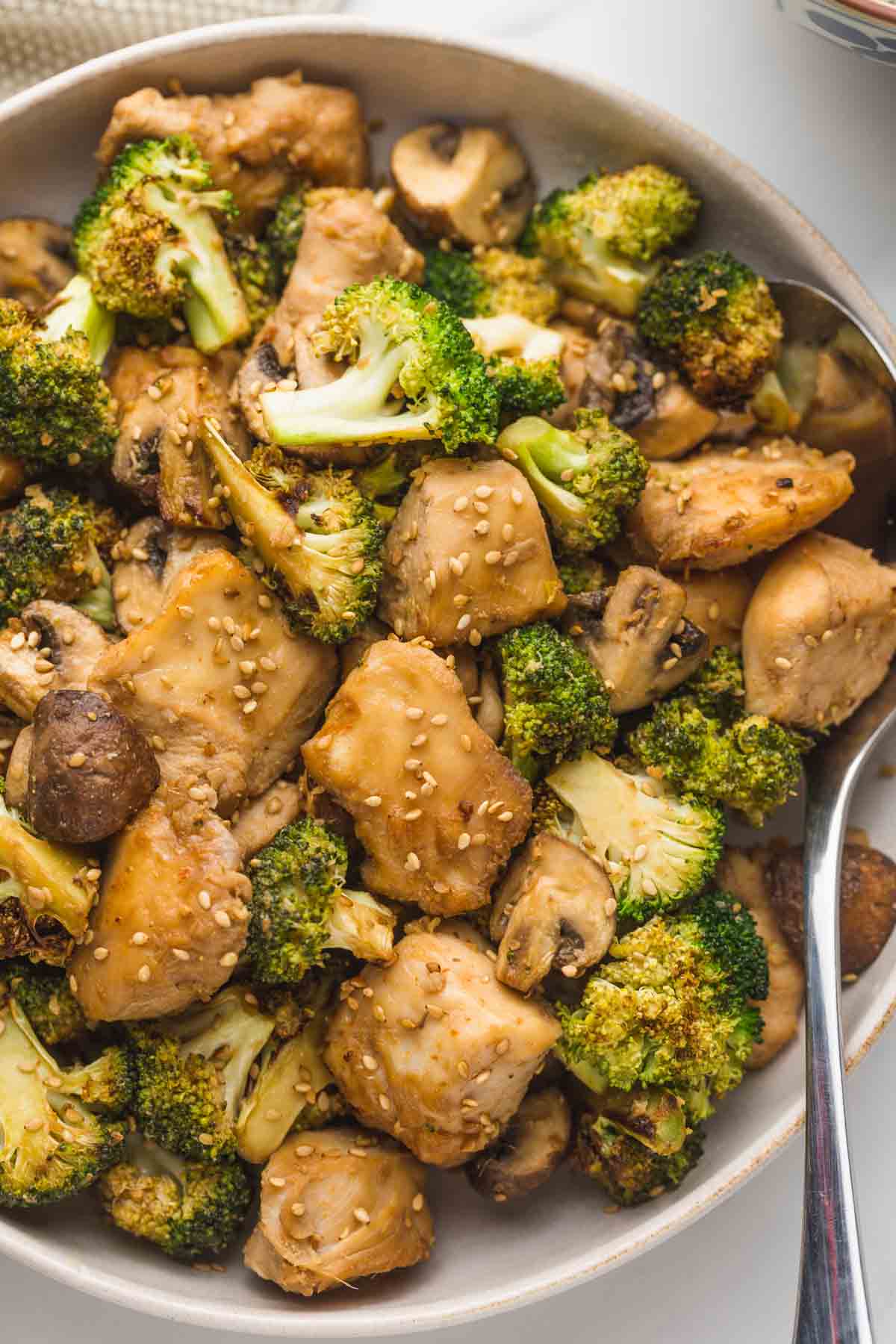 Chinese chicken and broccoli served in a beige bowl with a spoon