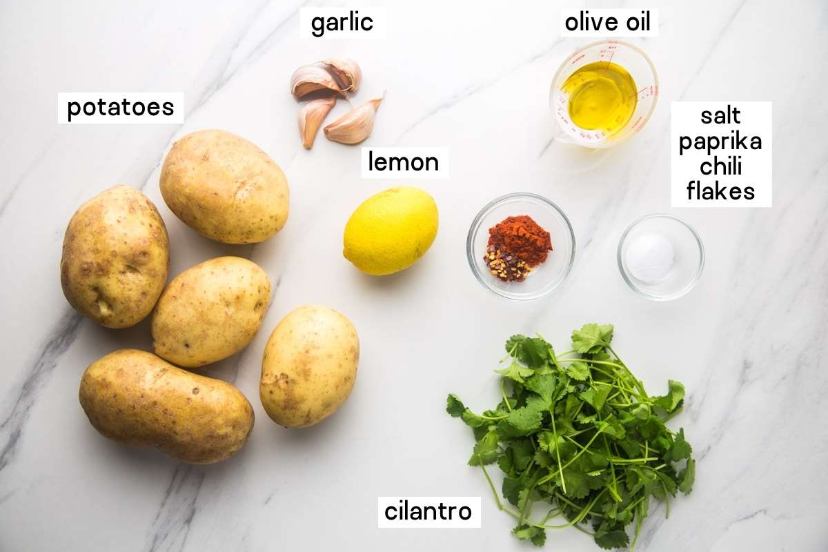 Ingredients needed to make batata harra; potatoes, garlic, lemon, olive oil, spices, salt and fresh cilantro.