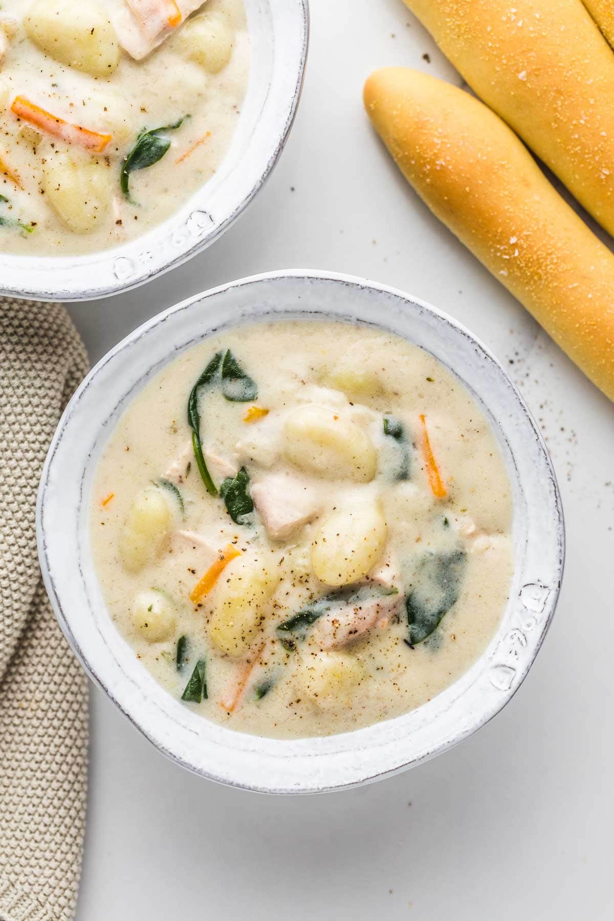 2 bowls of chicken gnocchi soup served with homemade breadsticks