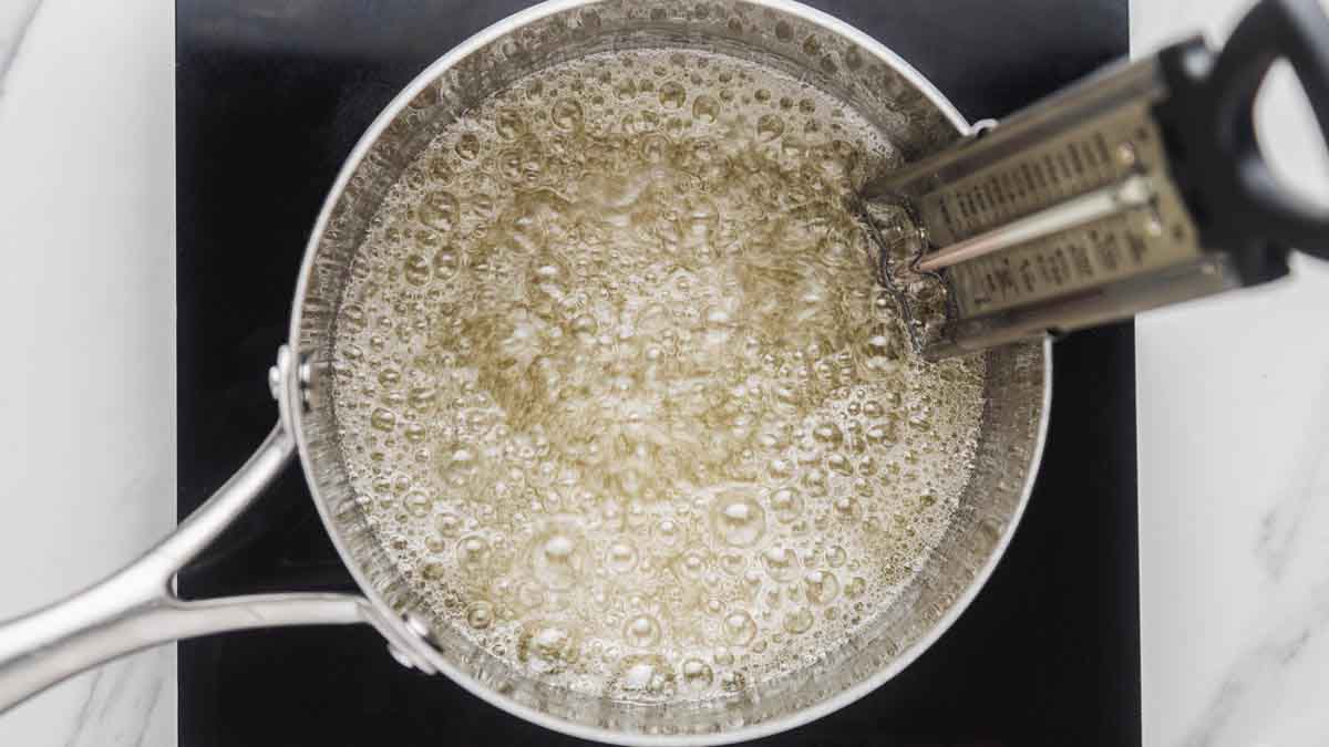 Boiling sugar mixture in a saucepan with a clip-on candy thermometer