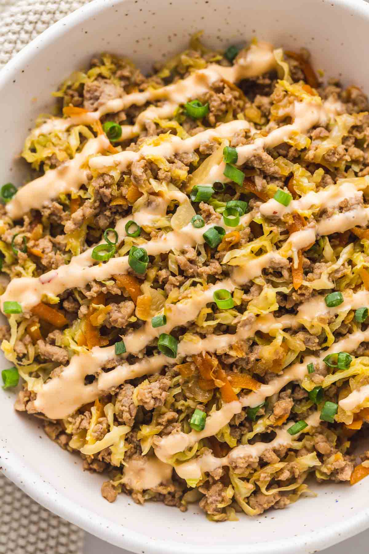 A close up of Egg Roll in a Bowl with creamy chili mayo drizzle