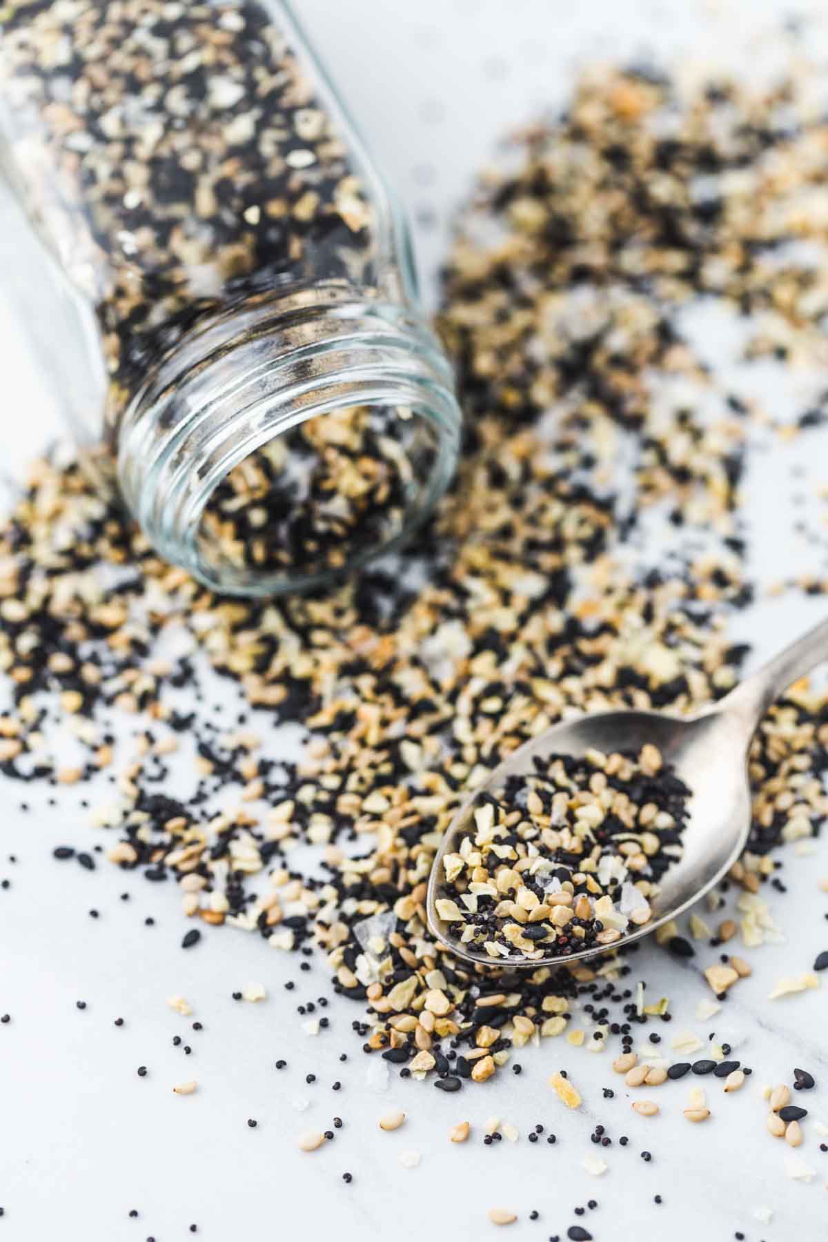 Everything Bagel Seasoning in a jar and on a spoon scattered everywhere