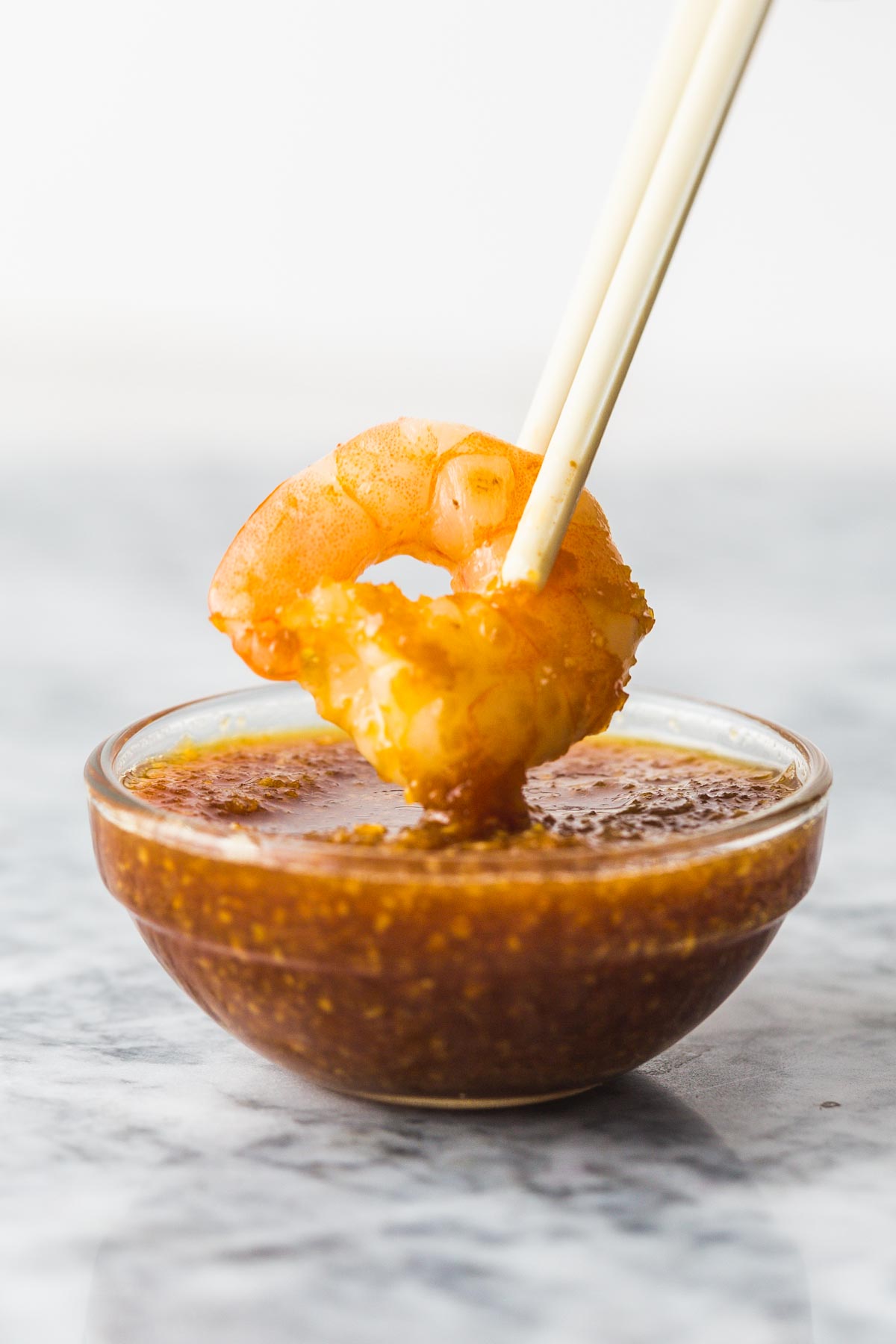 Dipping a shrimp with chopsticks into the ginger sauce