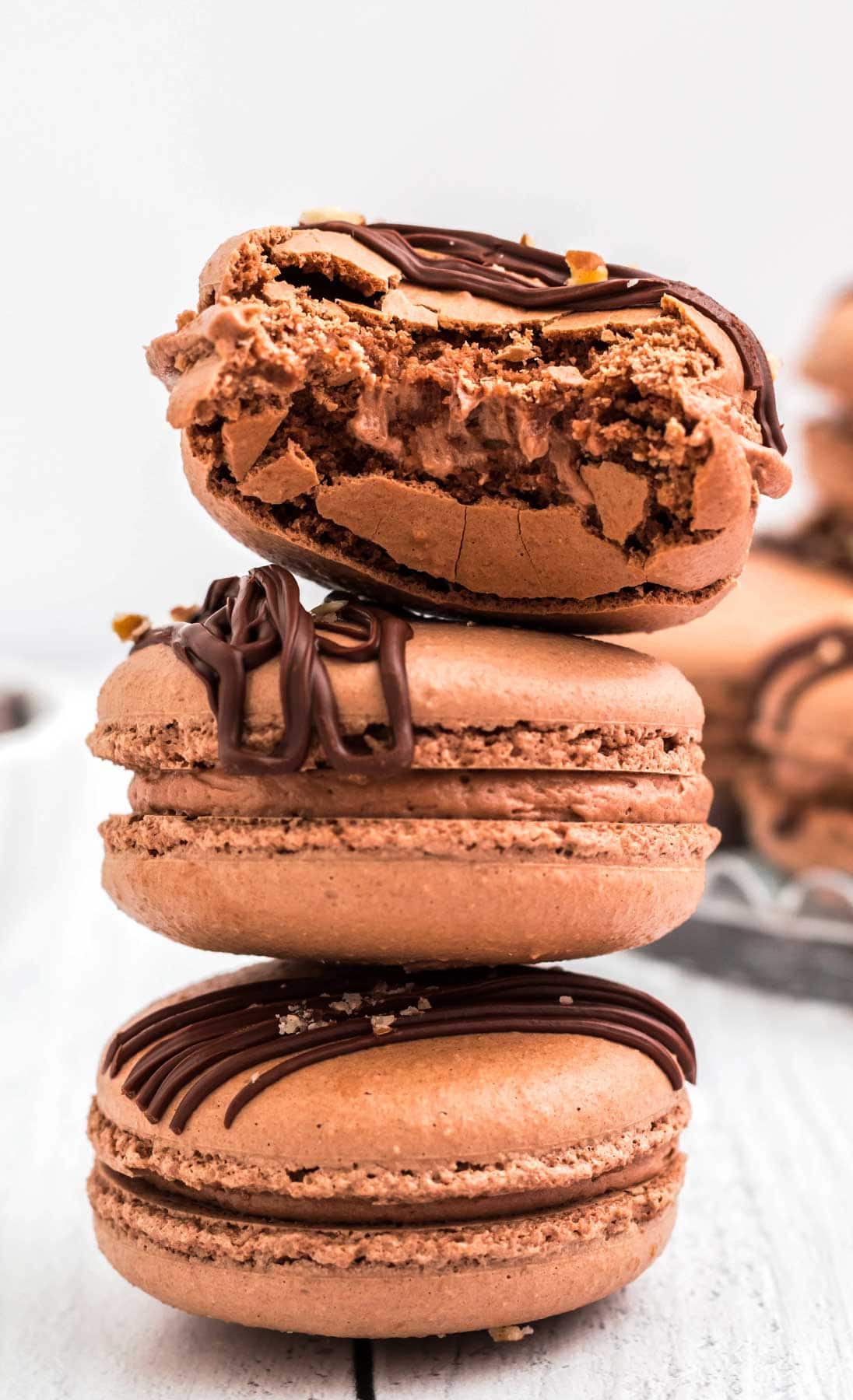 3 stacked chocolate macarons, and the top one is half eaten.
