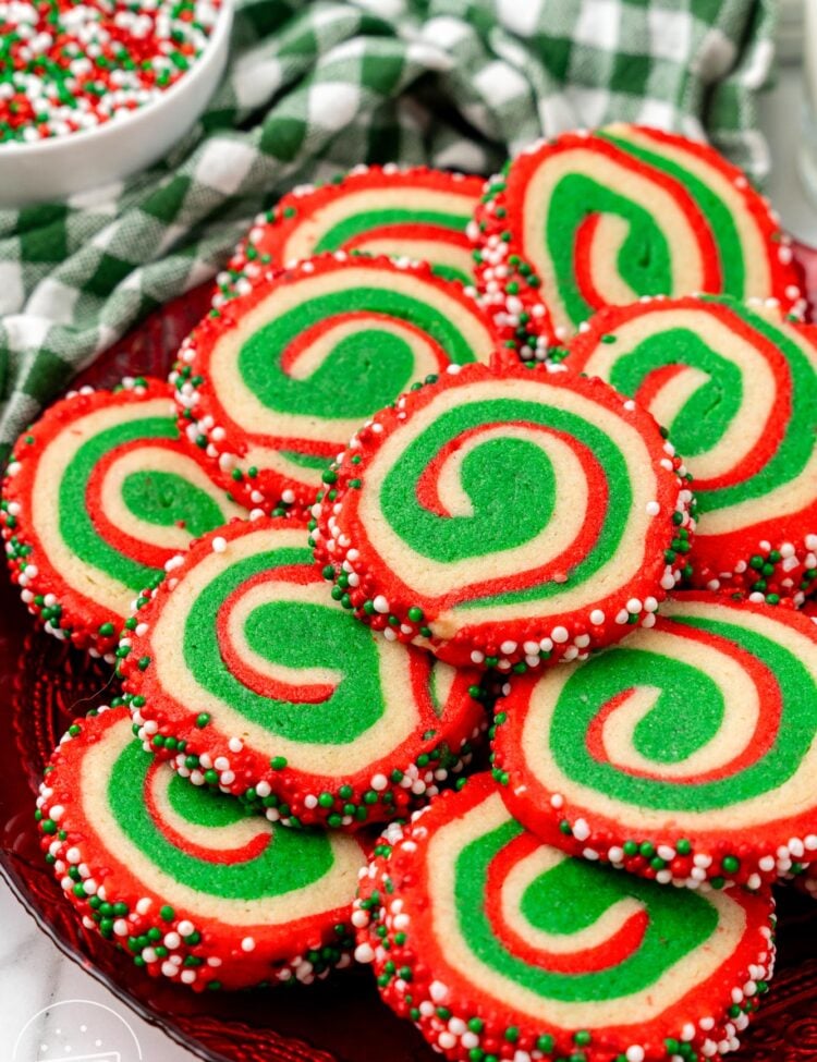 Christmas pinwheel cookies stacked on a festive red platter