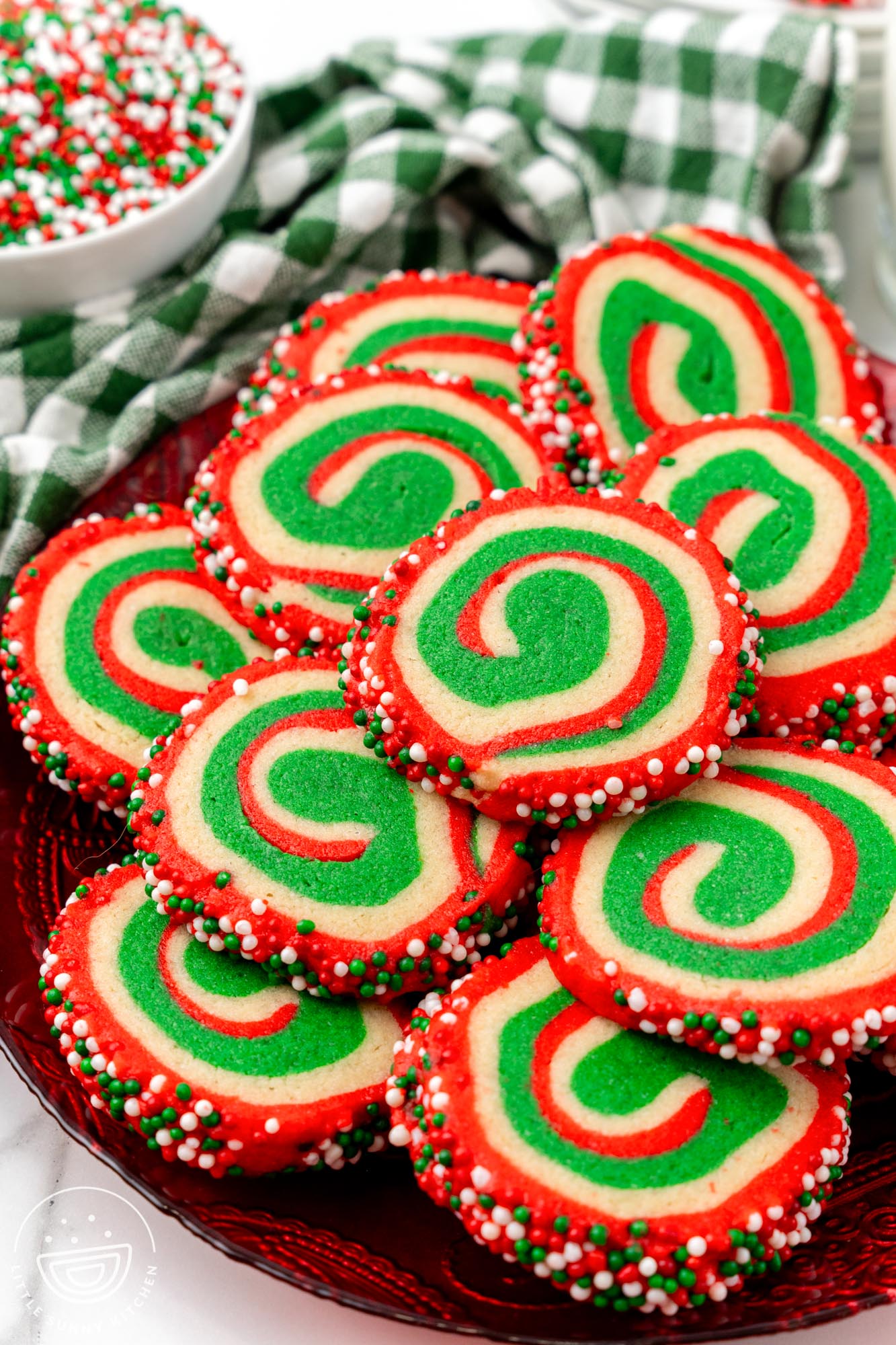 Christmas pinwheel cookies in vibrant red, green, and white colors stacked on a festive red platter