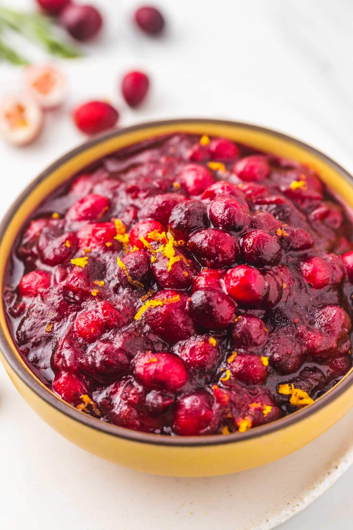 Cranberry sauce served in a yellow bowl garnish with orange zest