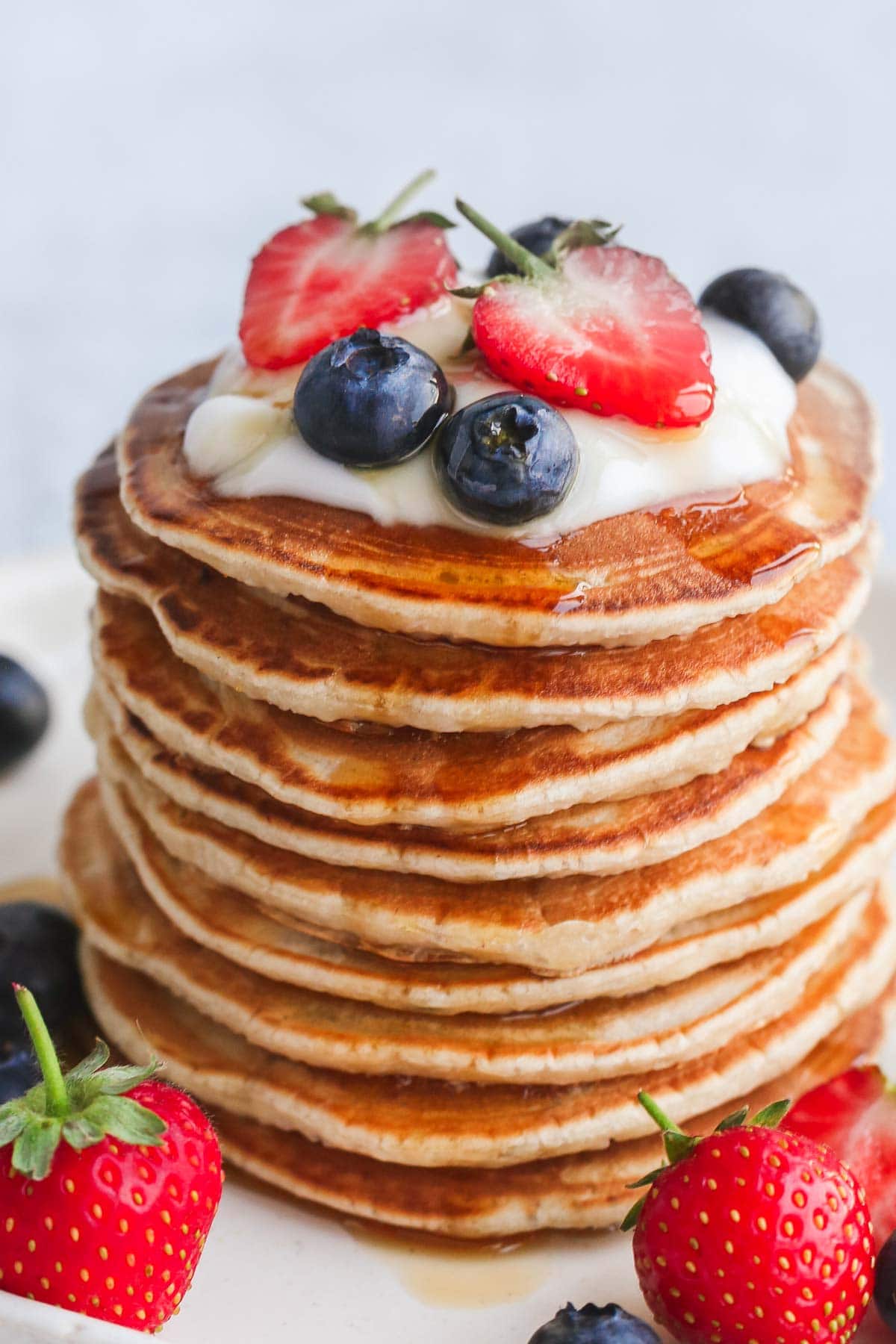 A close up of a stack of pancakes with fresh fruit